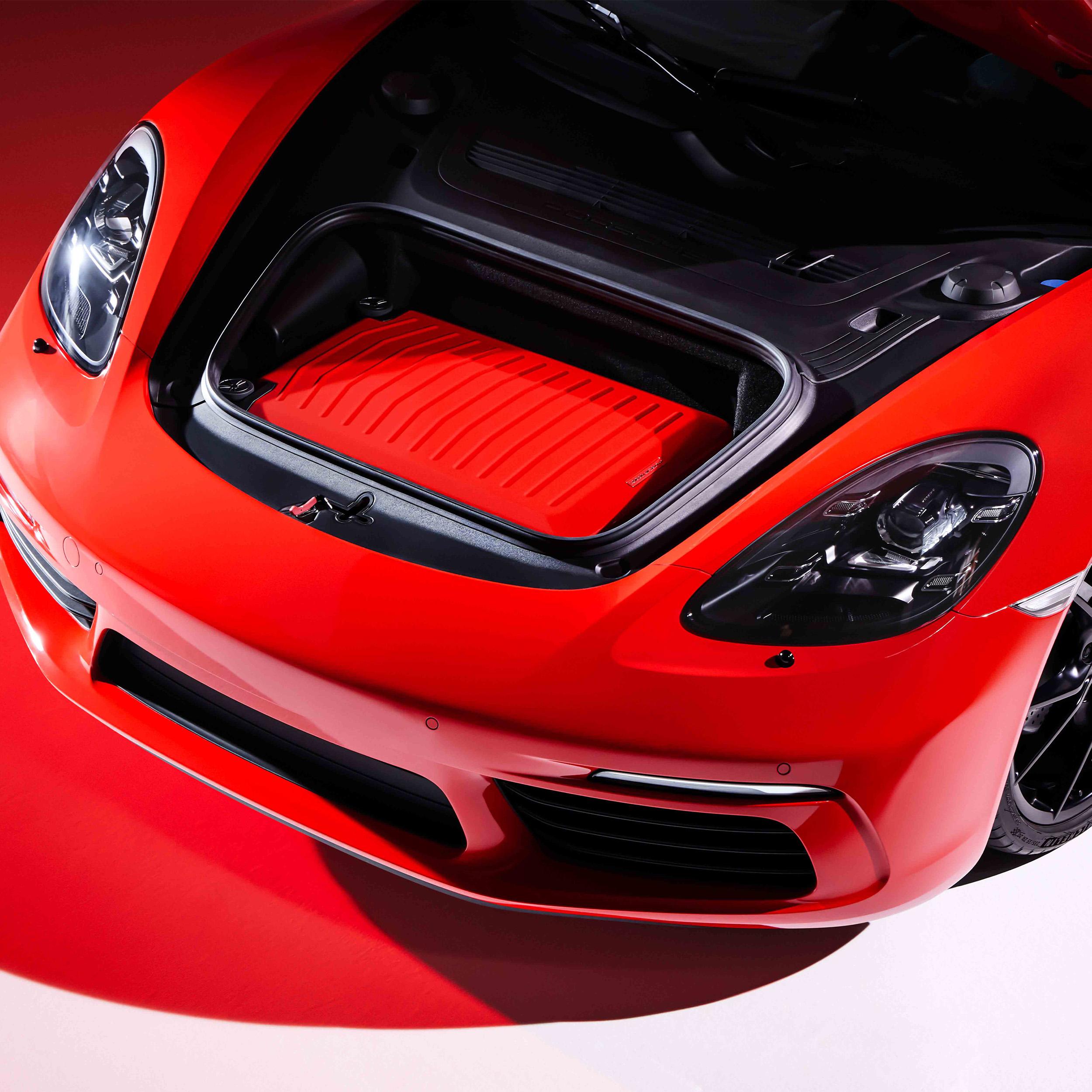 The open trunk of a red Porsche 911 containing a red Porsche Design Hardcase Trolley