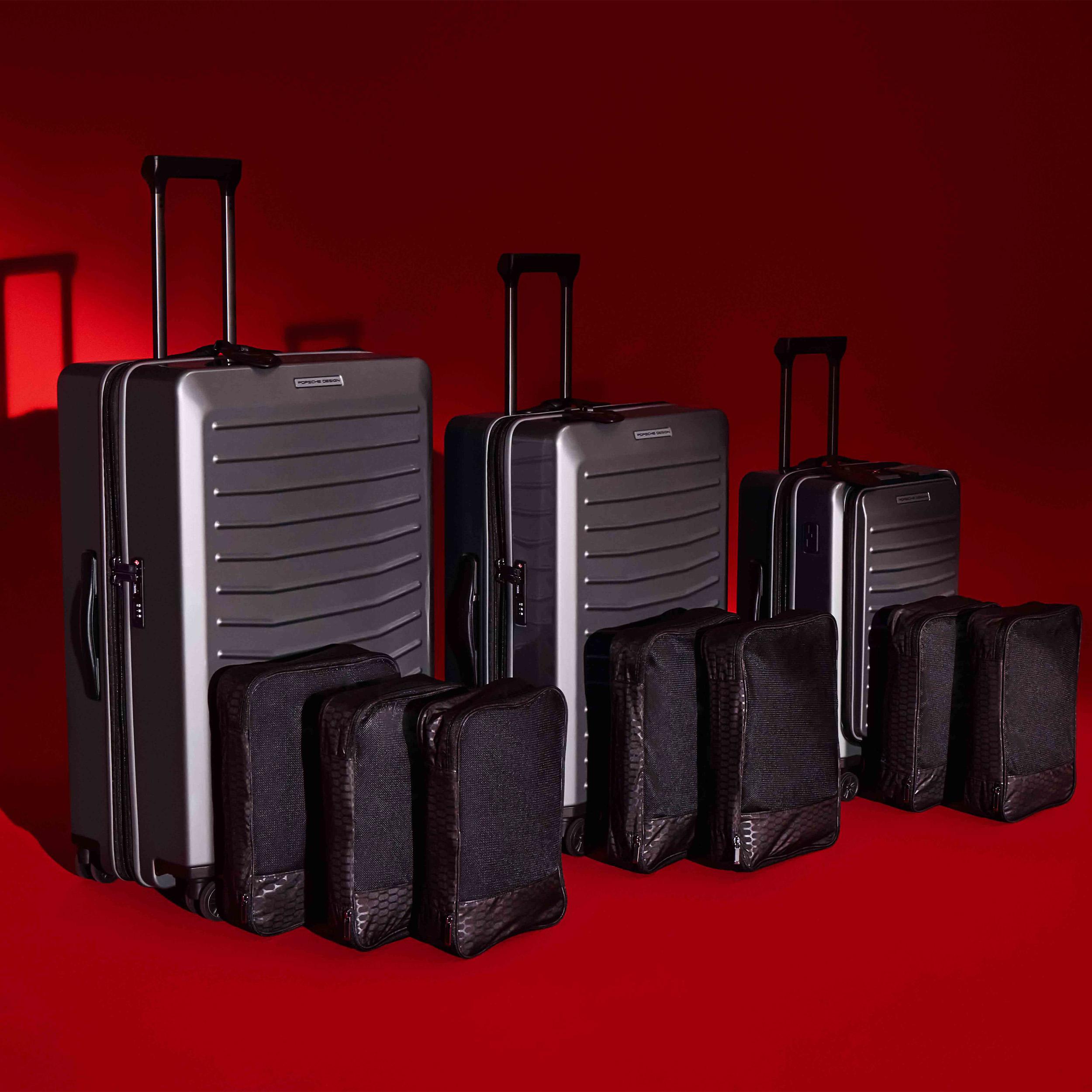 Threee black Porsche Design Hardcase Trolleys on a red background.