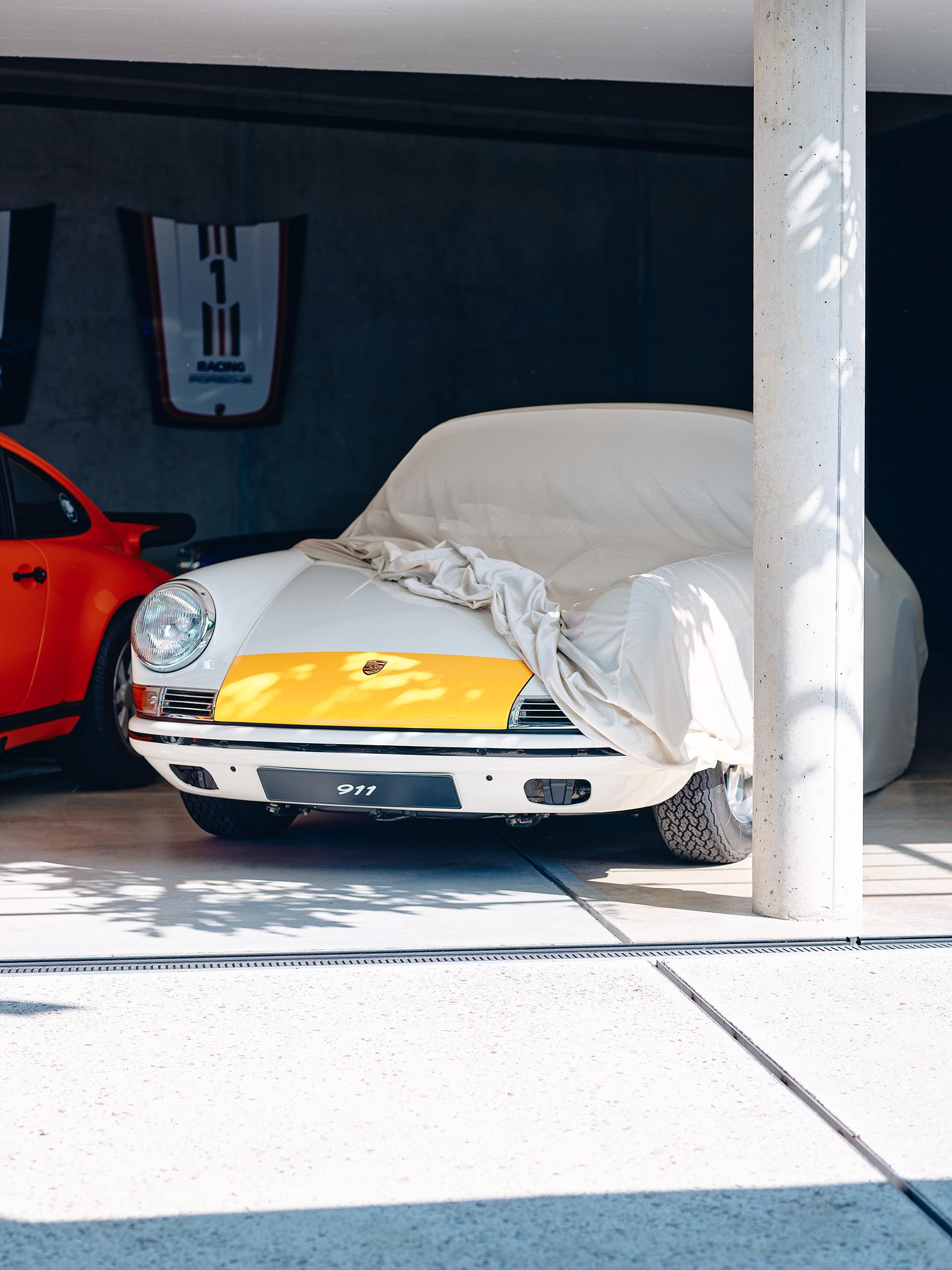 Pictured is a white yellow oldtimer Porsche in the Soul Garge with a white cover.