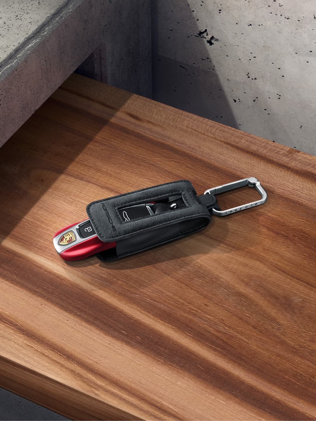 Porsche Tequipment keyring in black with a key in red on a table.