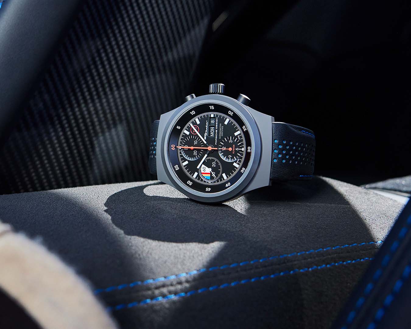 Na zdjęciu zegarek na rękę Porsche Chronograph 1 – 911 Dakar na zamszowym mankiecie, we wnętrzu samochodu.