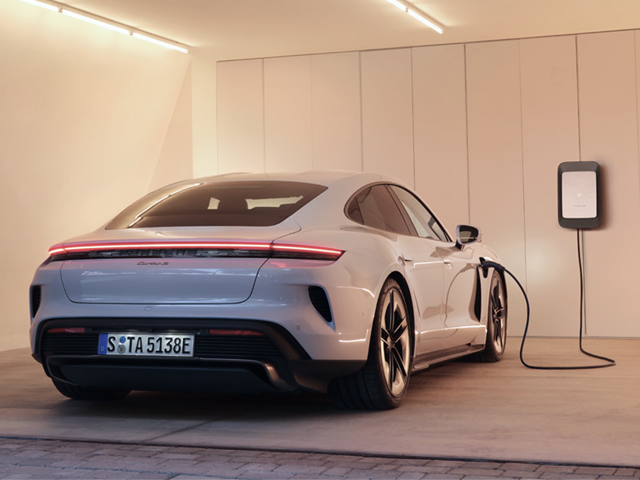 You can see a Porsche Taycan in a garage next to a Porsche wallbox