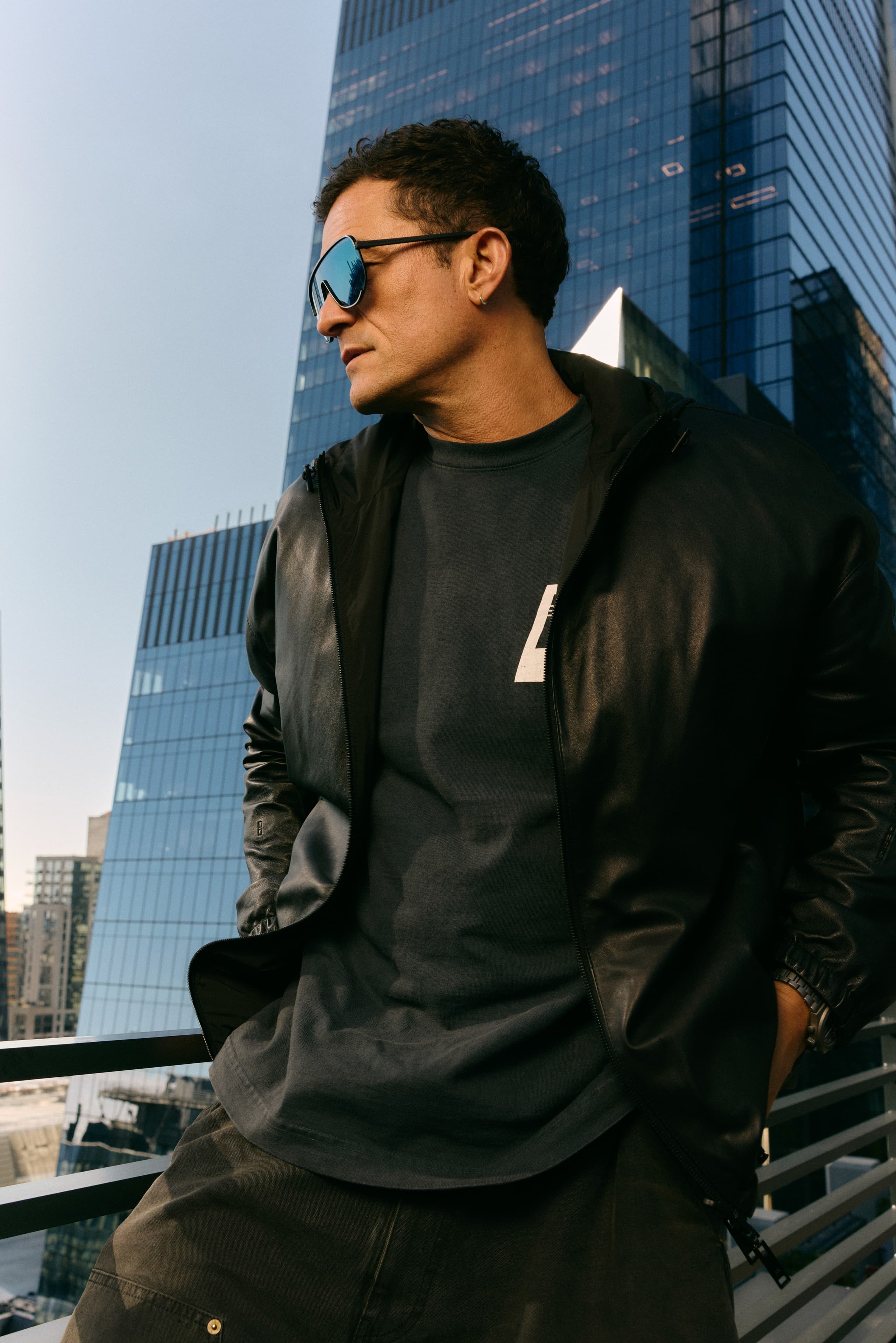 Orlando Bloom wears the Porsche Design Targa #1 Eyewear series, looks to the left in front of a building.