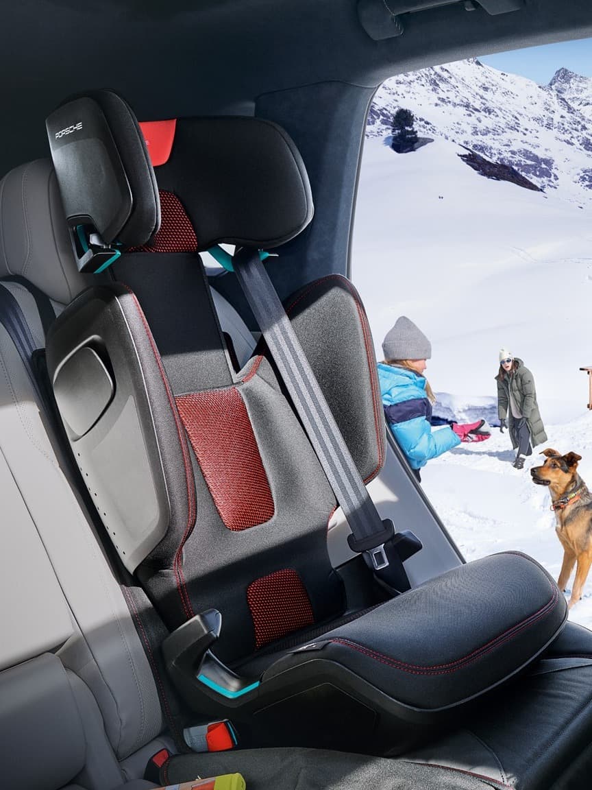 Manuais e brochuras da Porsche sobre uma mesa de madeira com capas vermelhas, imagens de carros e registos de manutenção numa oficina.