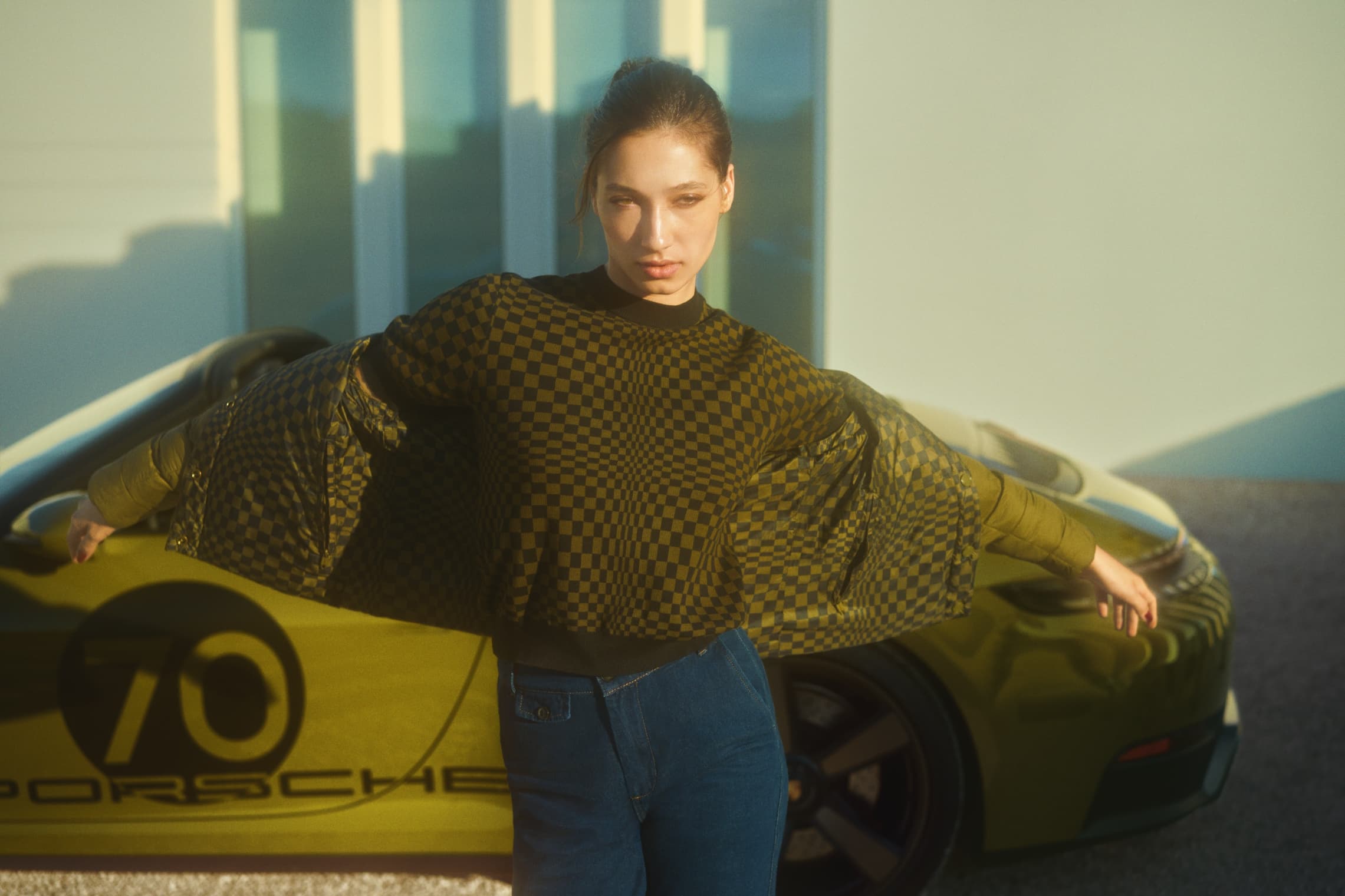 Woman wearing Porsche clothing from the new 911 Spirit Collection. Porsche in back.