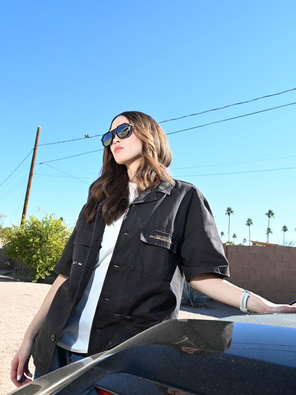 Close up of women wearing Porsche Design sunglasses standing next to a Porsche