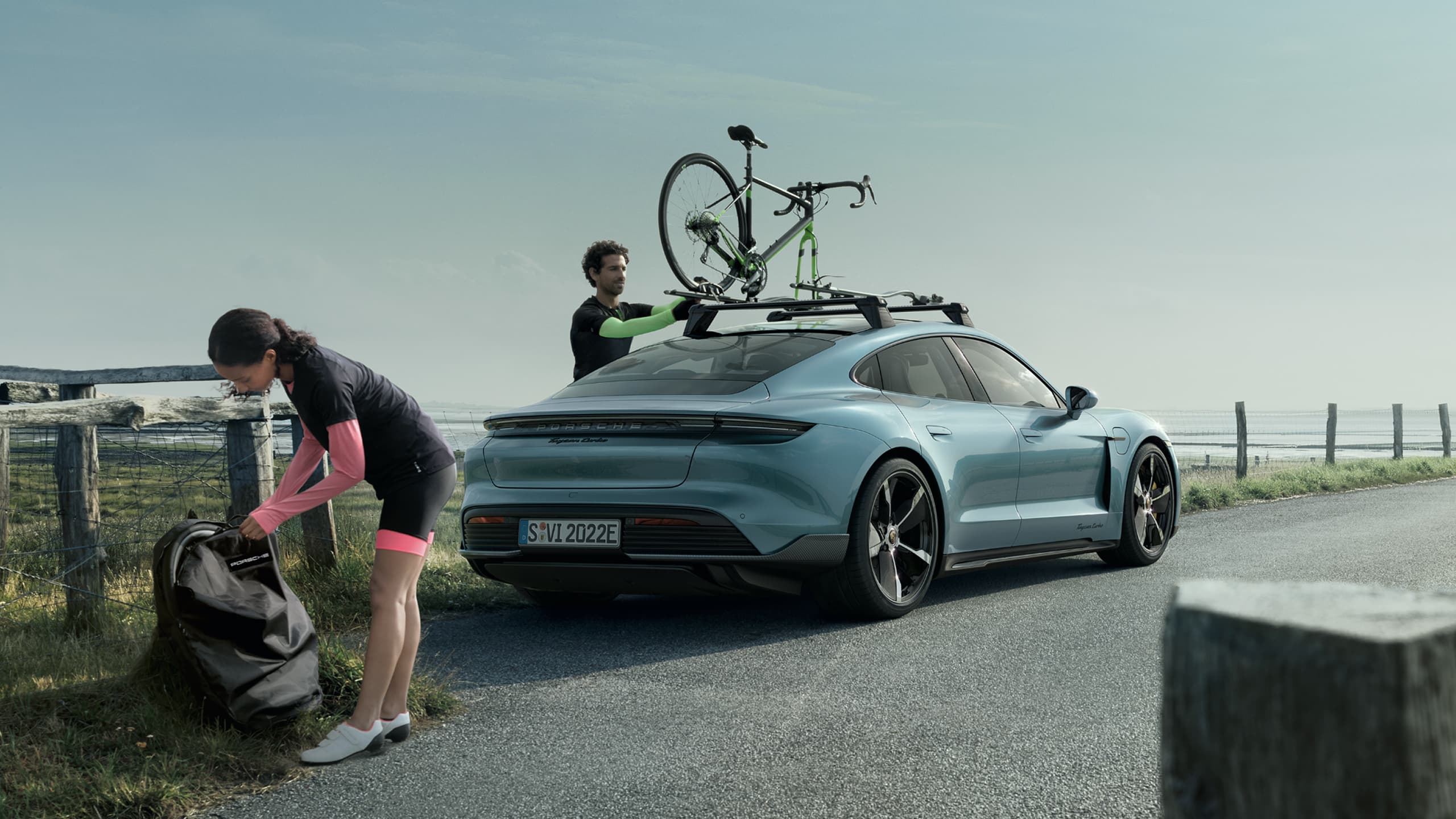 You can see two person next to their blue Porsche Taycan