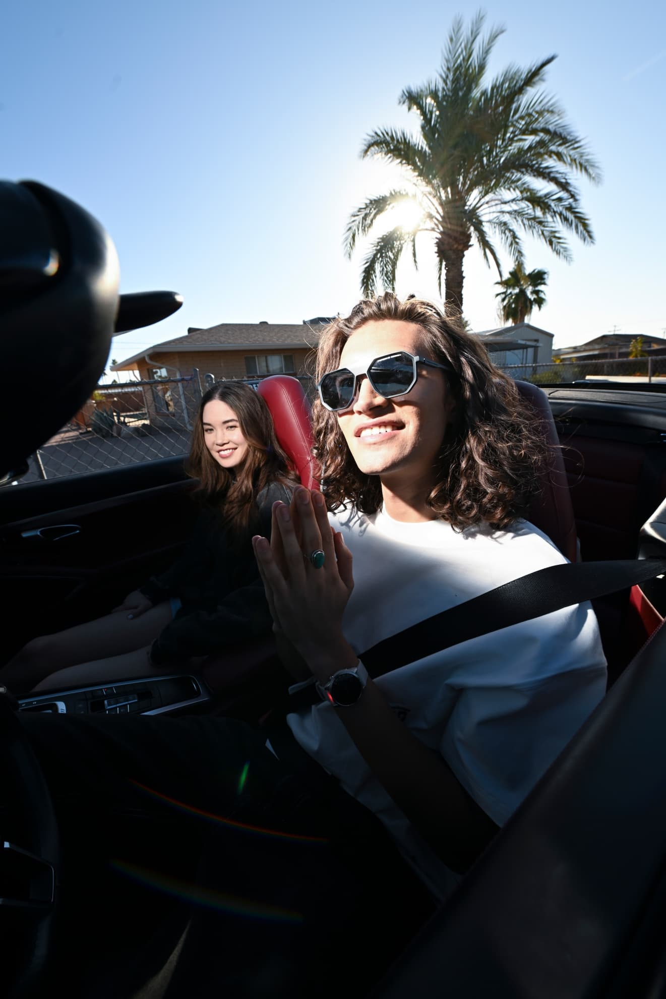Two people riding in a convertible black Porsche 911