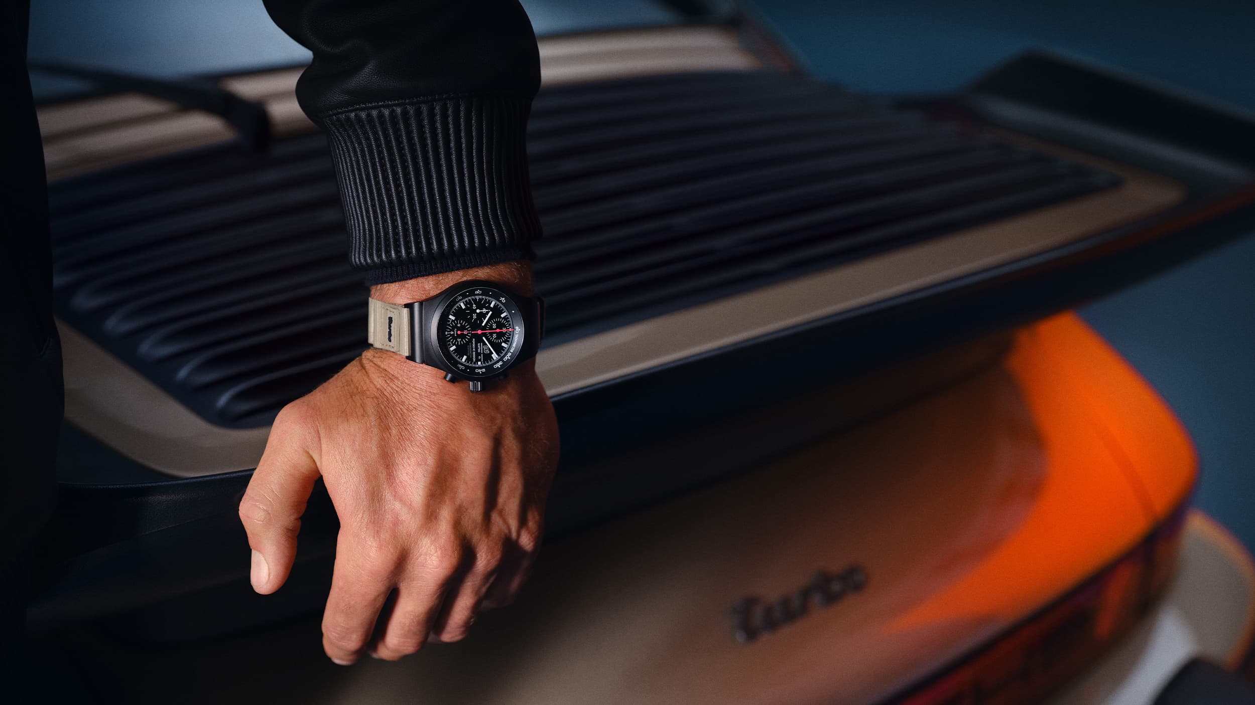 Man is leaning on a car wearing 50Y Chronograph