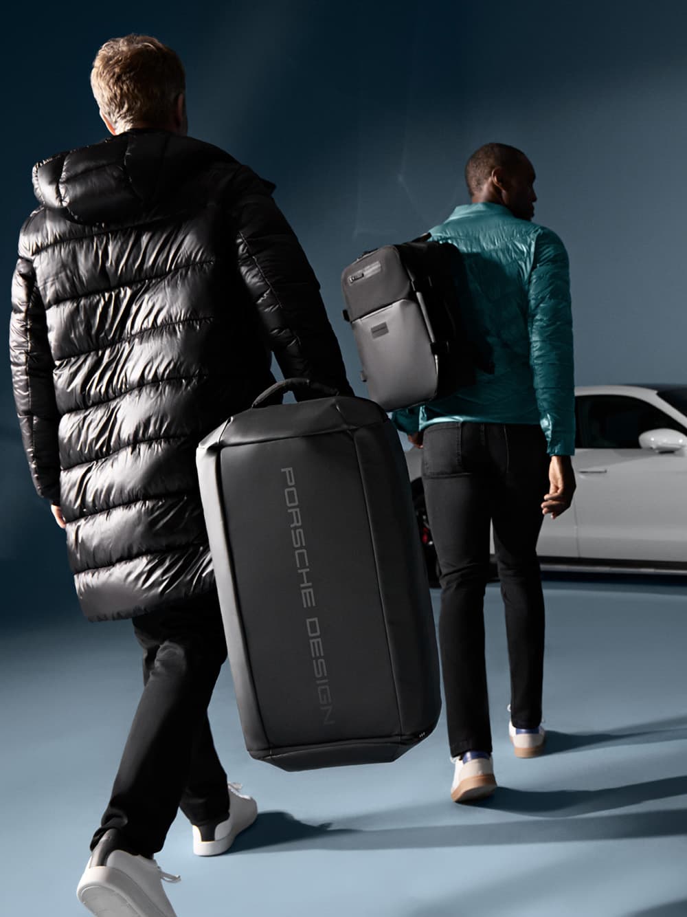 Woman standing in front of a Porsche Taycan and posing with a red hardcase trolley suitcase from Porsche Design.