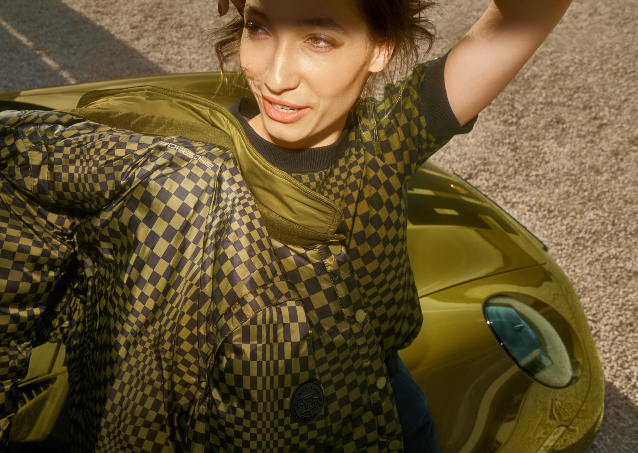 Woman wears clothes from the Porsche 911 Spirit 70 collection with Pasha pattern in Olive Neo