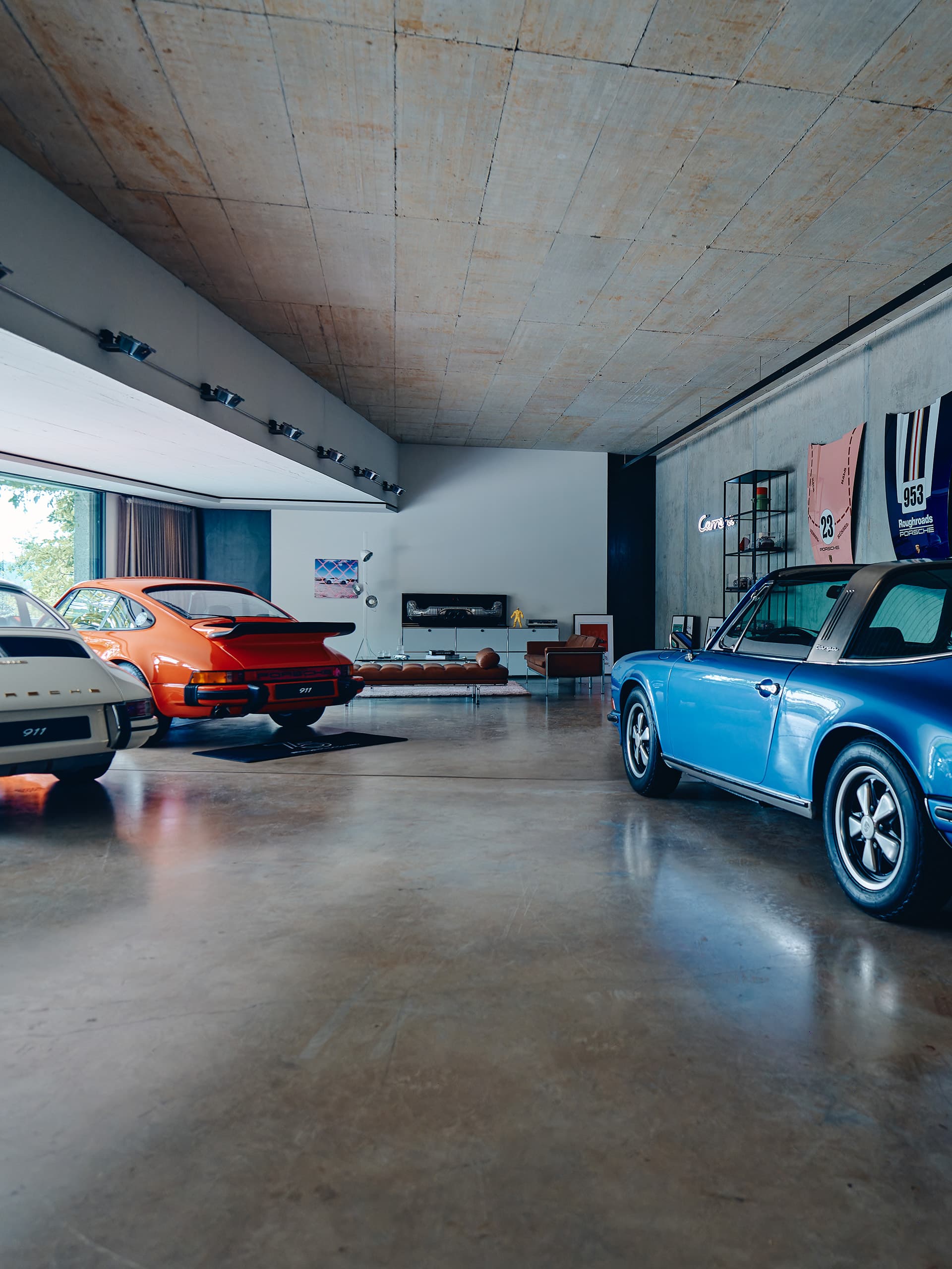 Pictured are three oldtimer Porsche in the color blue, orange and white in a soul garage.