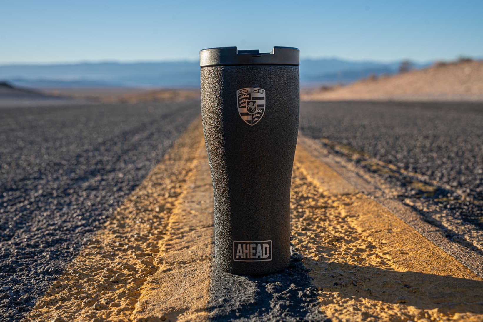 Porsche AHEAD thermo cup standing on highway road