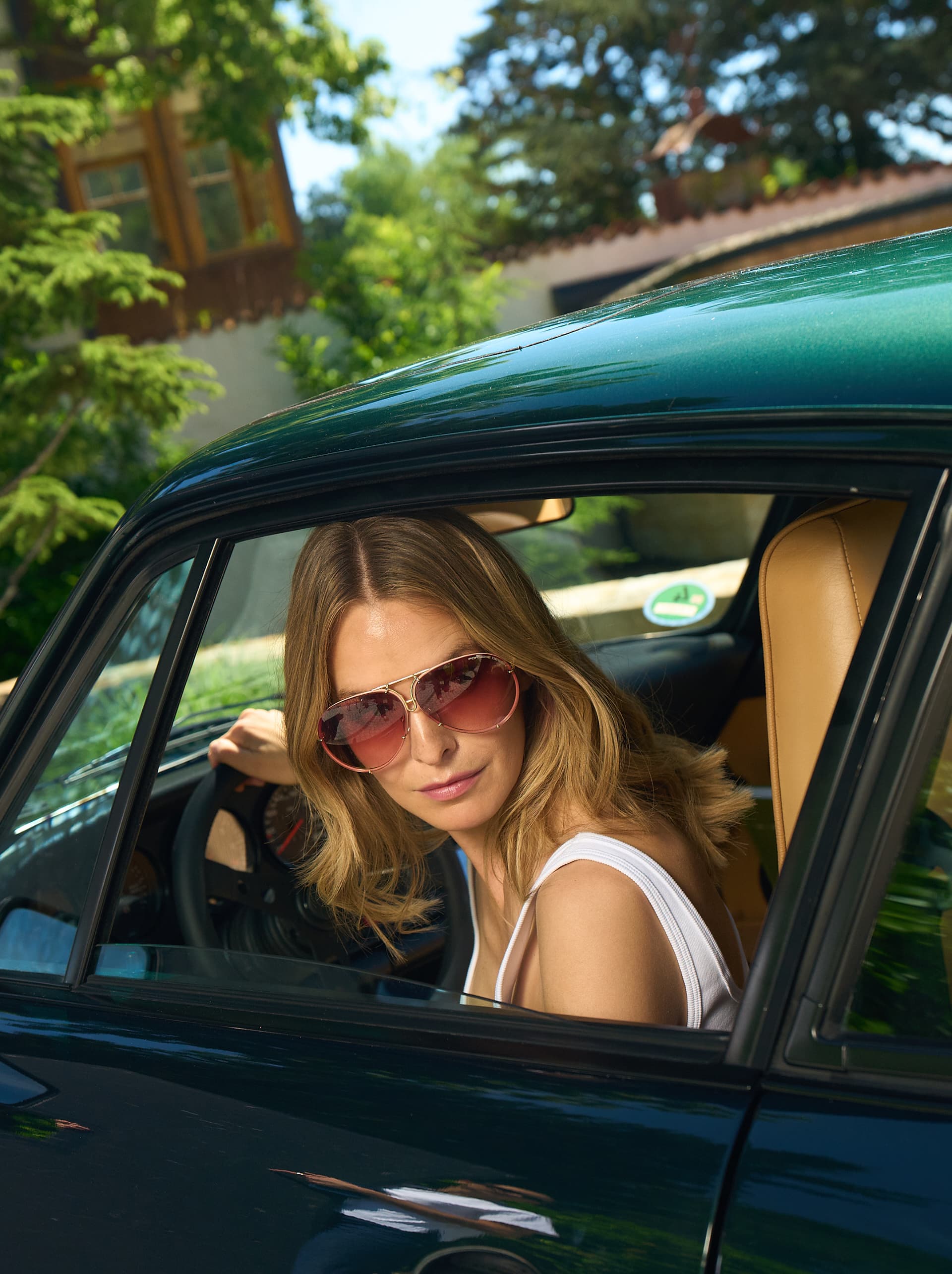 Vrouw zit in een groene 993 en draagt Porsche Design-zonnebril