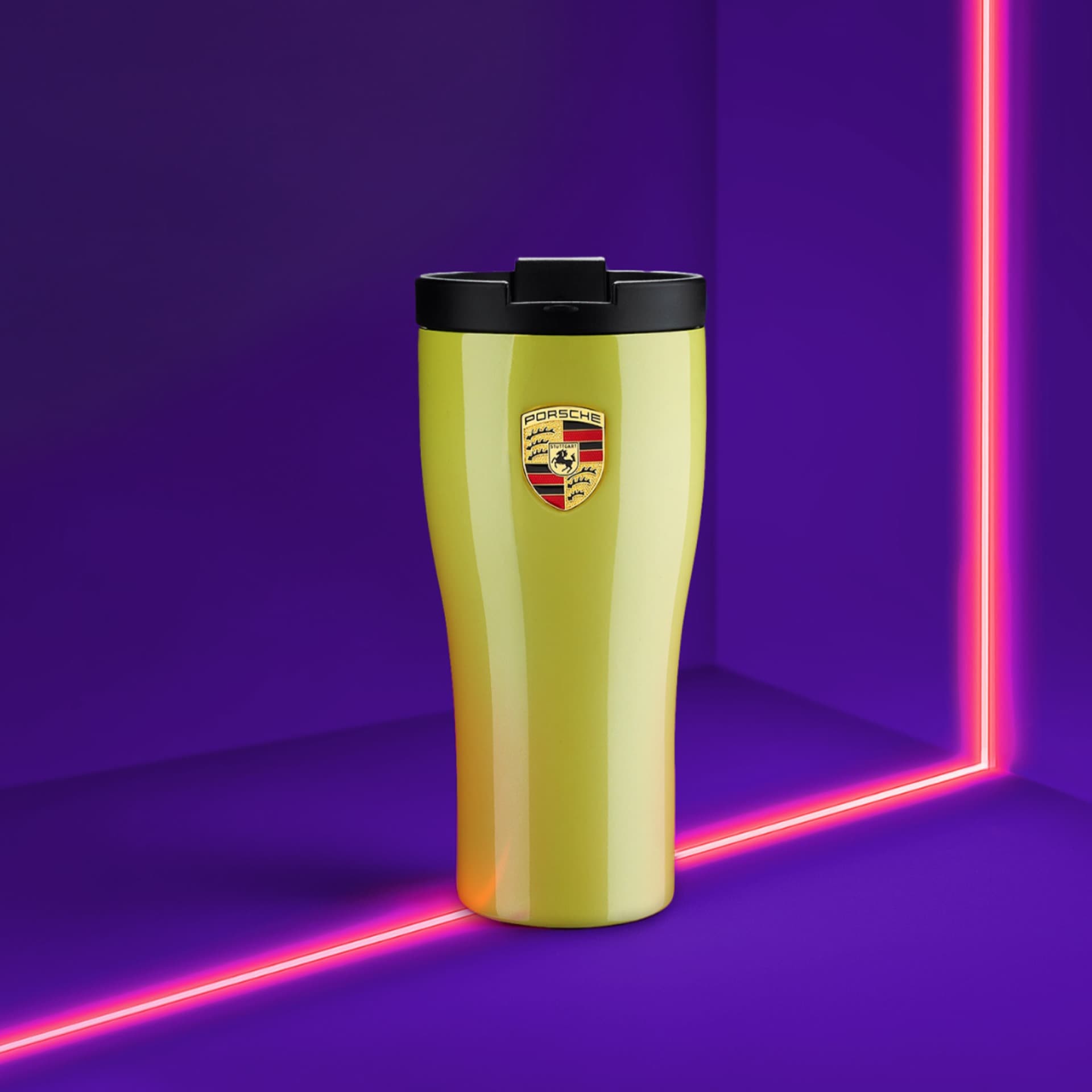 Yellow Porsche travel mug with black lid, logo on front, set against a vibrant purple background with pink neon lines