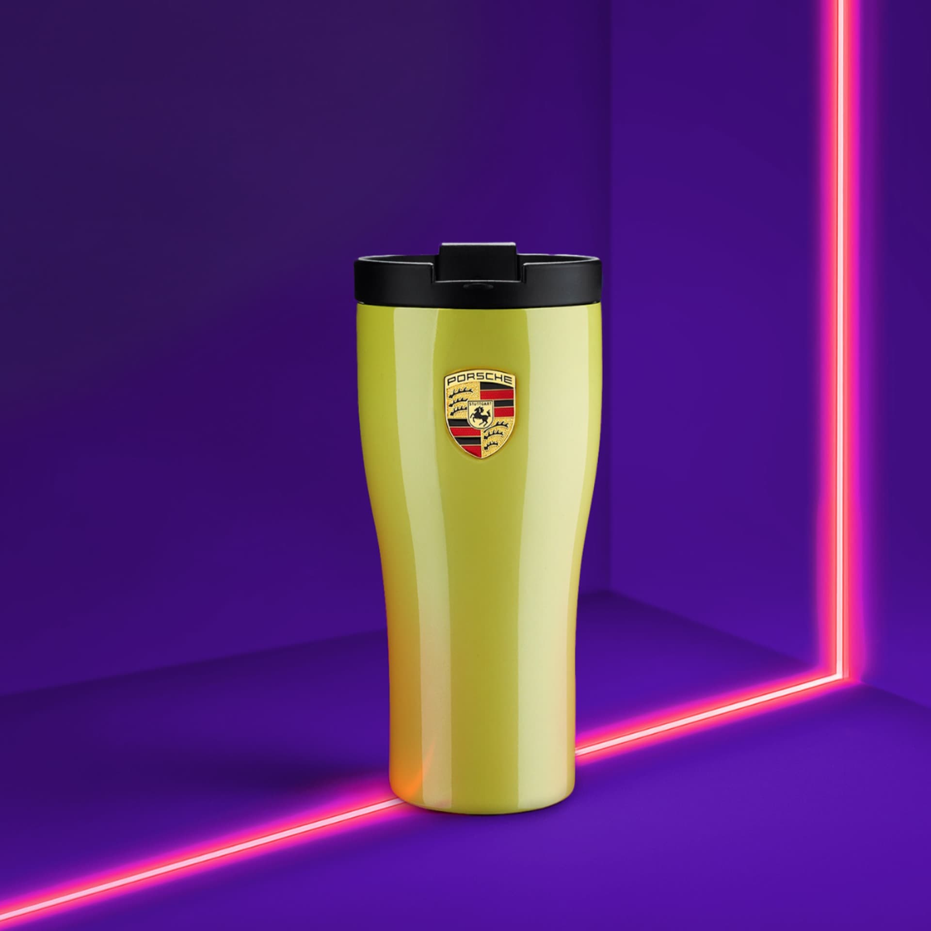 Yellow Porsche travel mug with black lid, logo on front, set against a vibrant purple background with pink neon lines