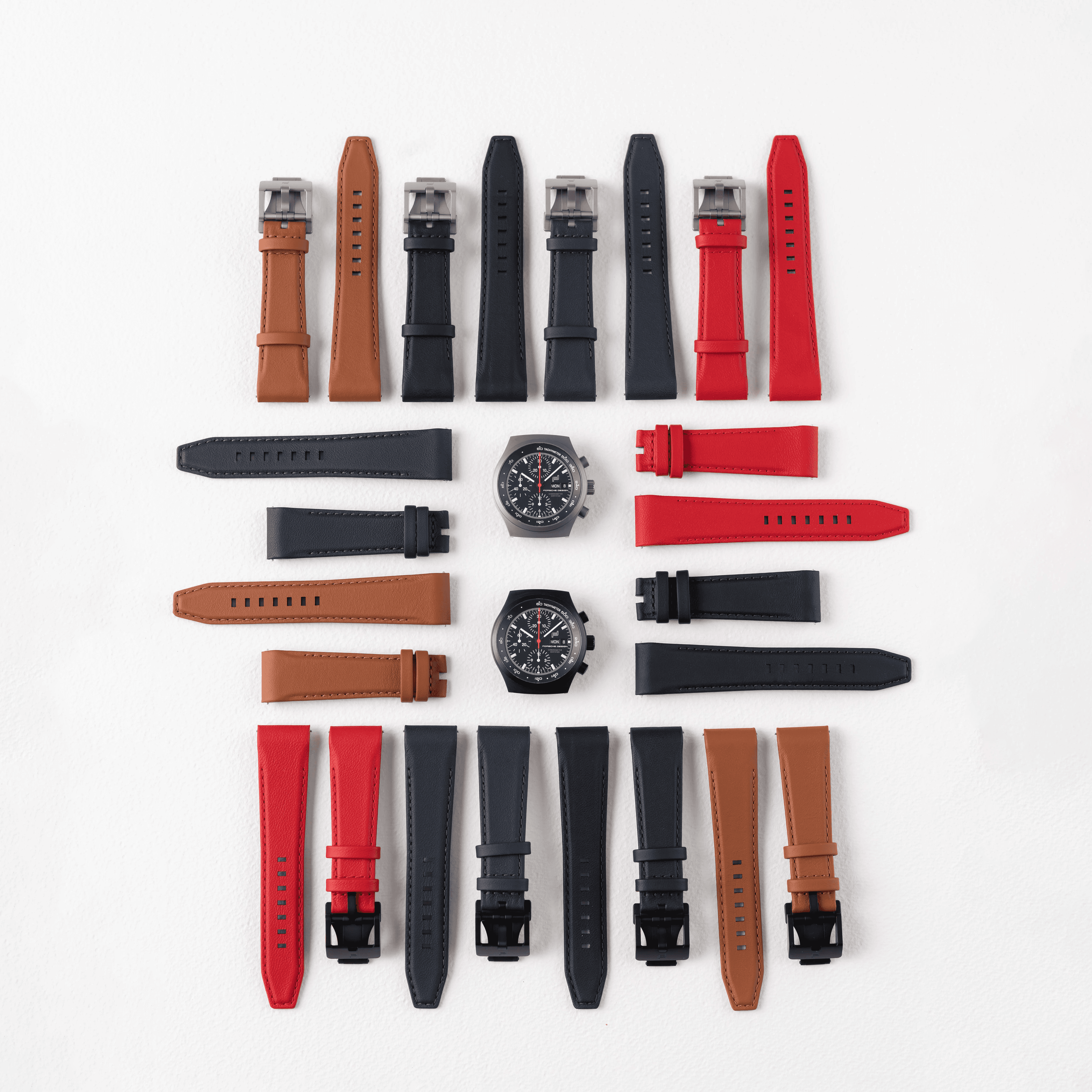Various leather watch straps with two chronograph watches on a white background.