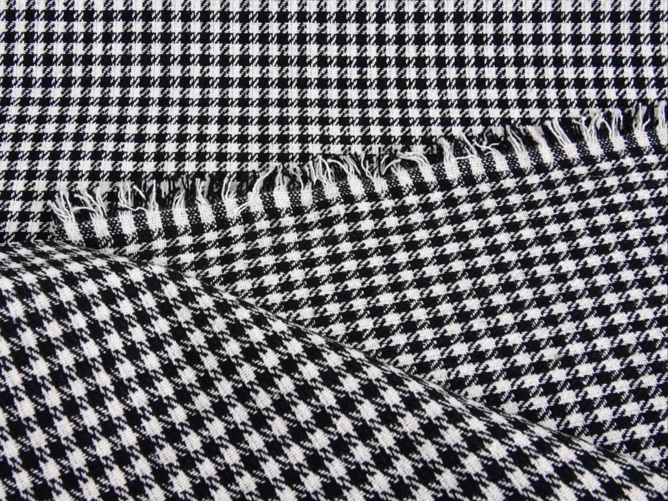 Close-up of a black-and-white houndstooth scarf with fringed edges.