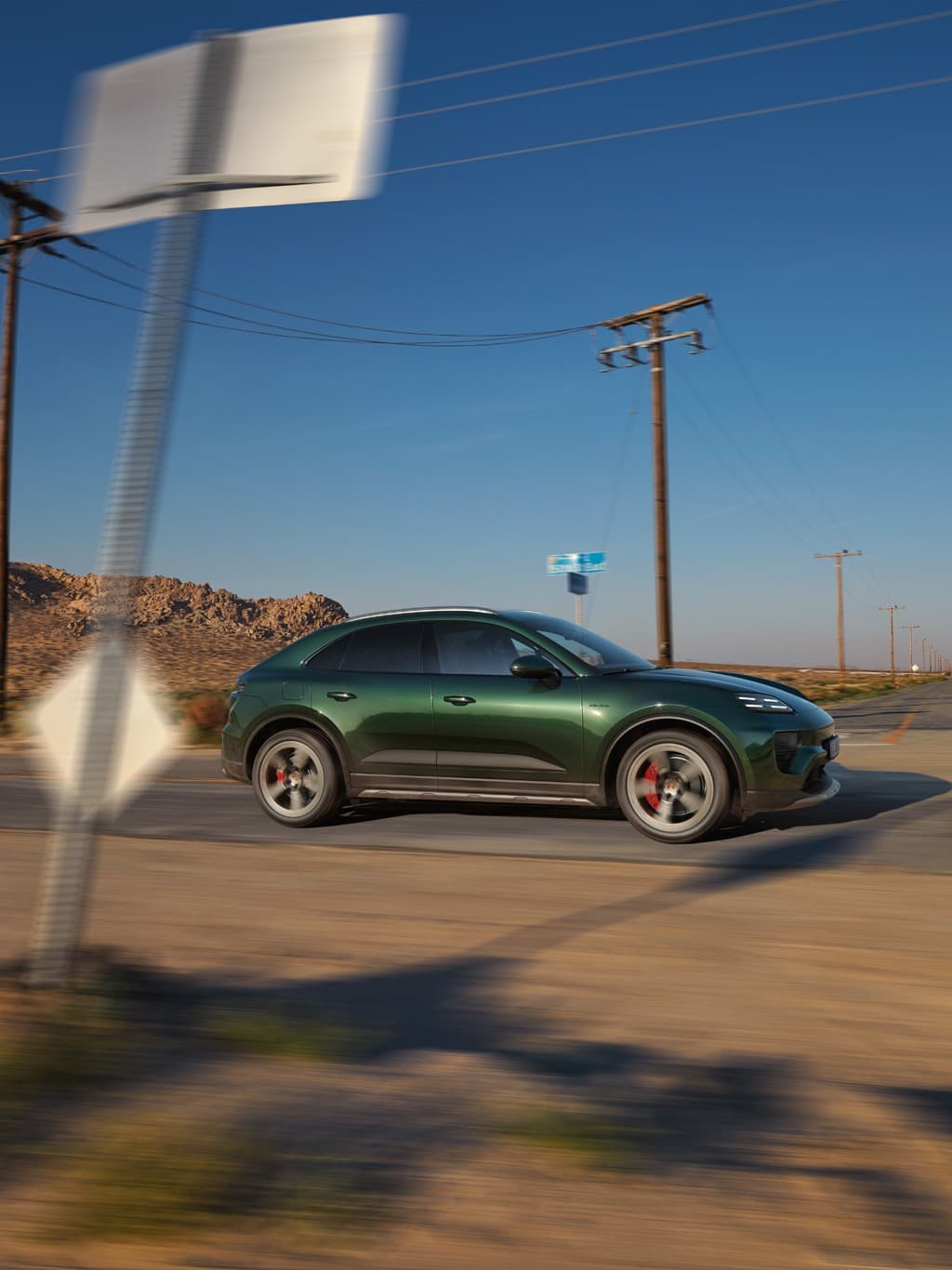 Darkgreen Porsche Macan driving on a street