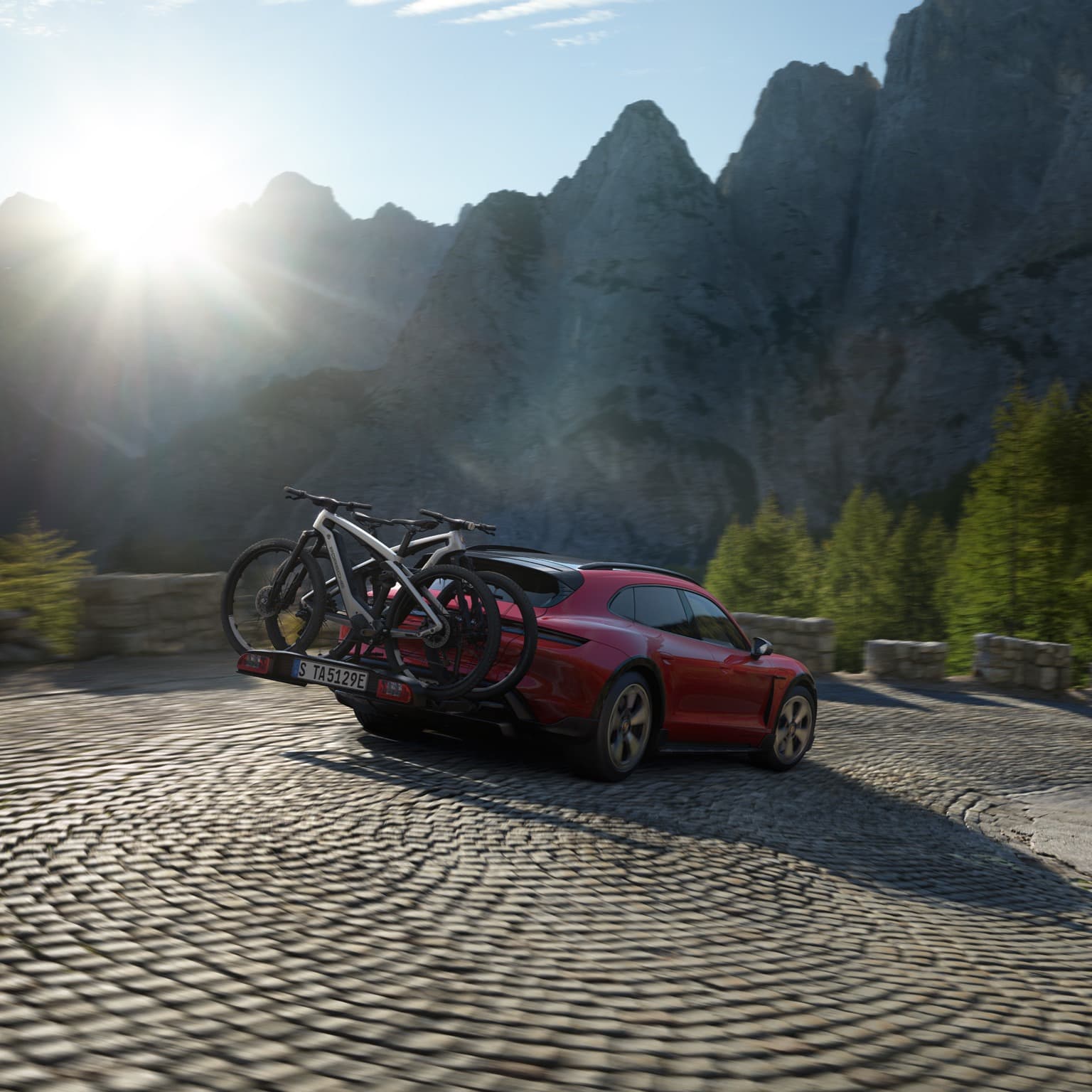 Red car driving thorugh a road in the mountains with a bike rack