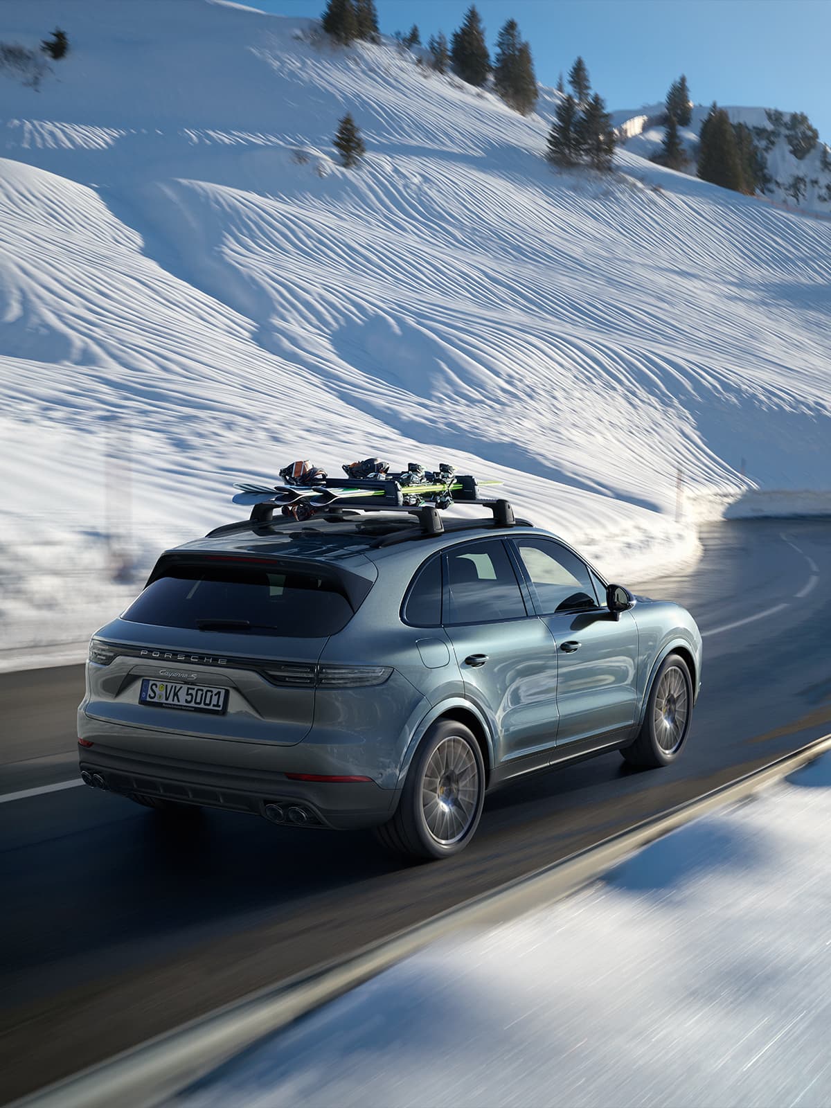 Couple with skis by a black Porsche Taycan in snowy cabin setting, man loading roof box, winter scene.