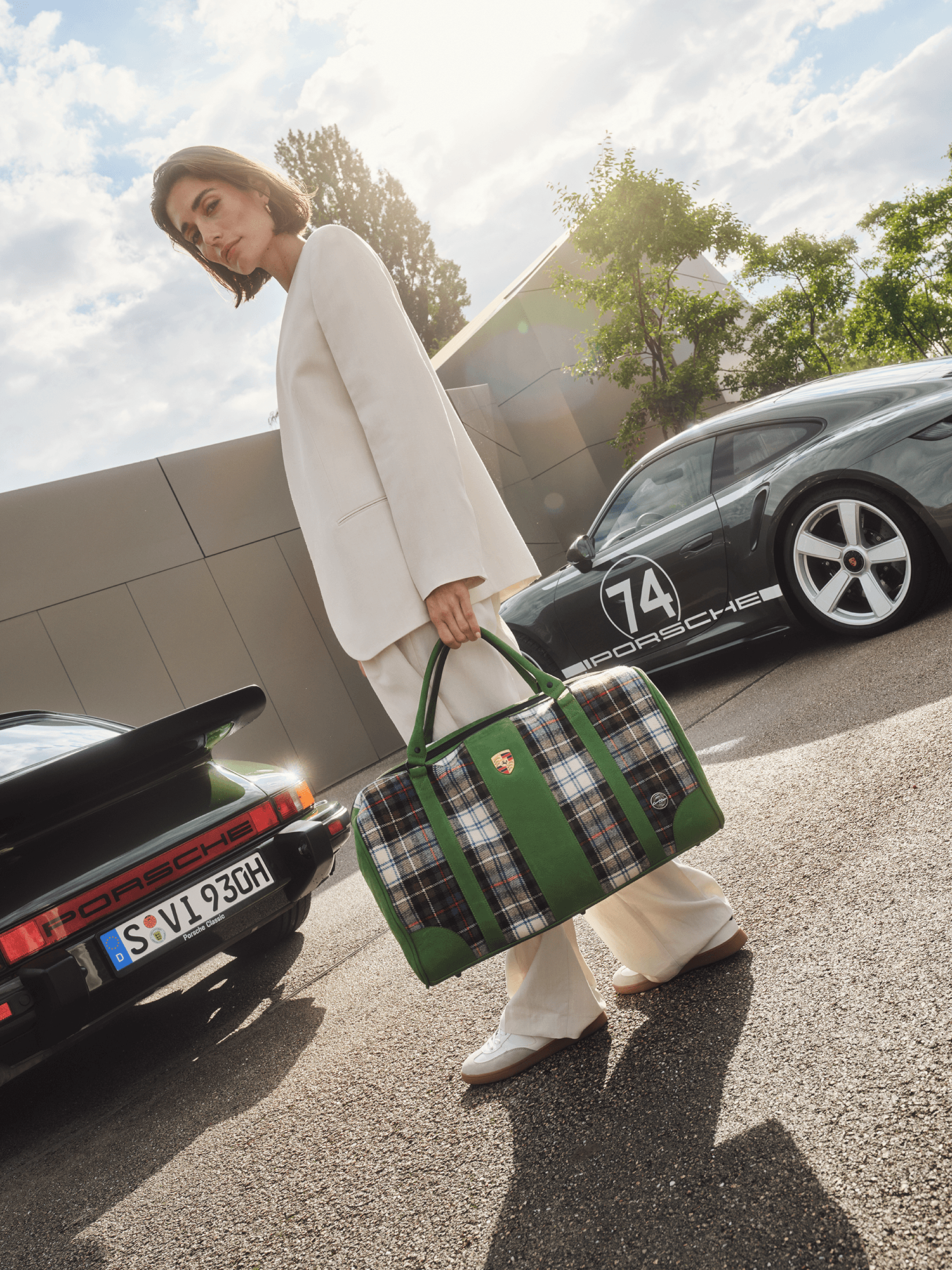 A lady holding a Touring Bag next to a Porsche 911