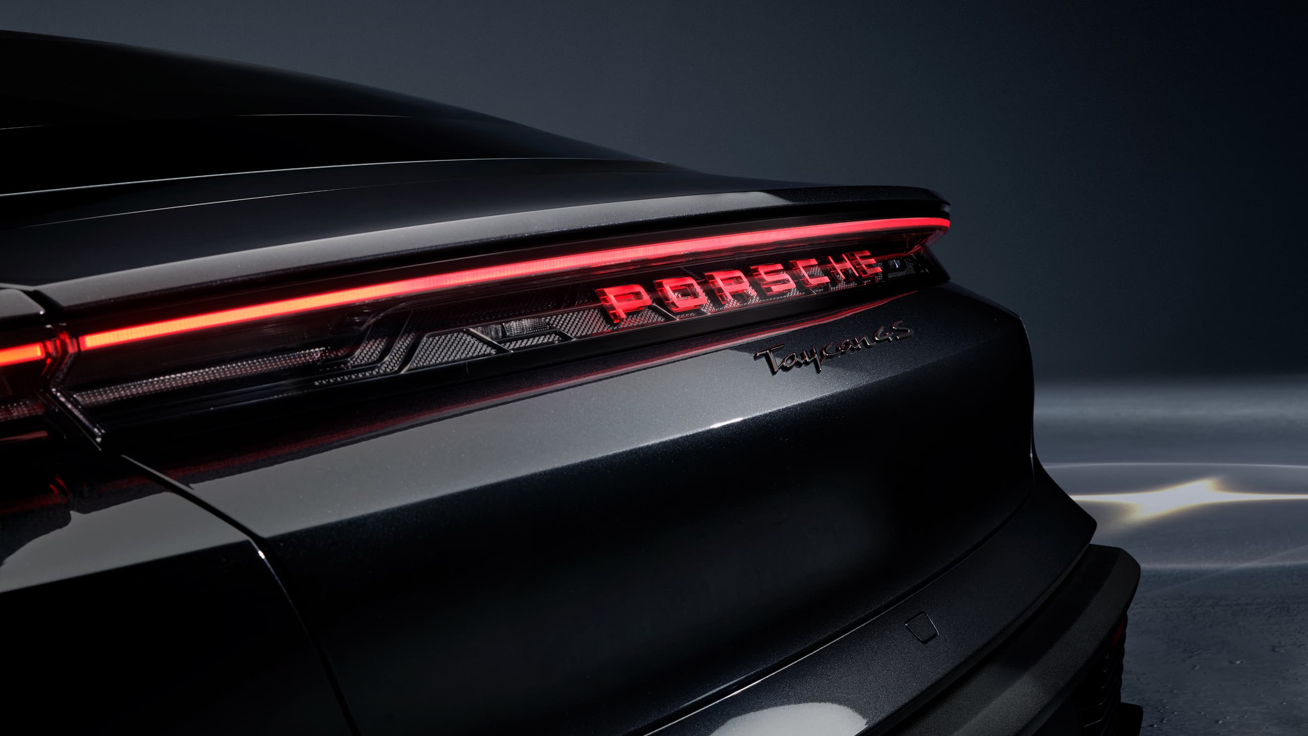 You can see the rear of a black Porsche Taycan in focus