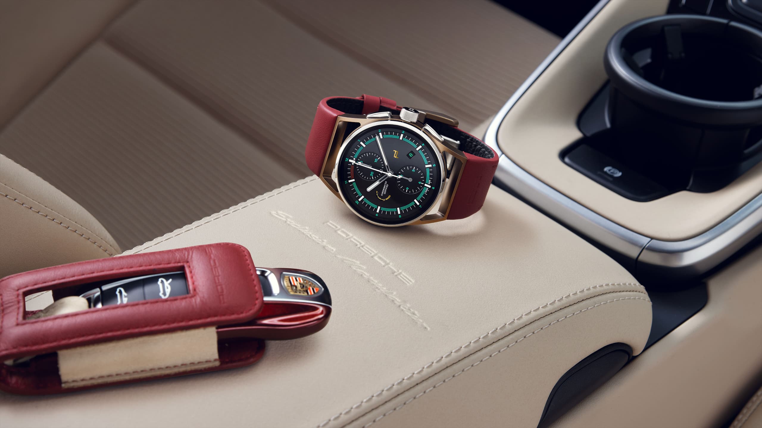 Na zdjęciu chronograf 911 Targa 4S Heritage Design Edition z czerwonym paskiem oraz kluczyk do samochodu Porsche na beżowym skórzanym tle we wnętrzu samochodu Porsche.