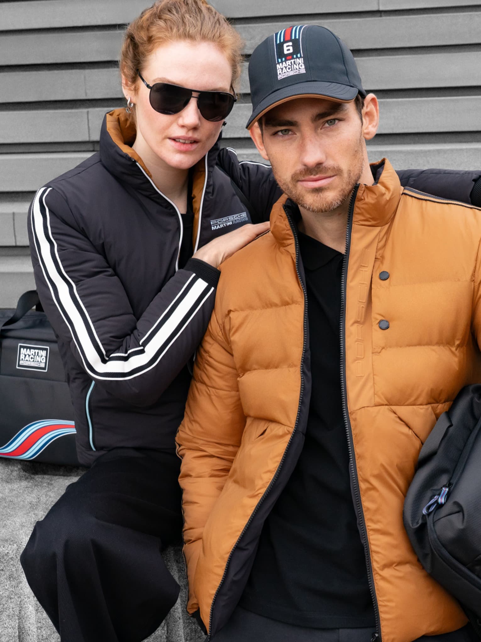 You can see a man and a woman next to each other wearing Porsche Martini Racing clothing