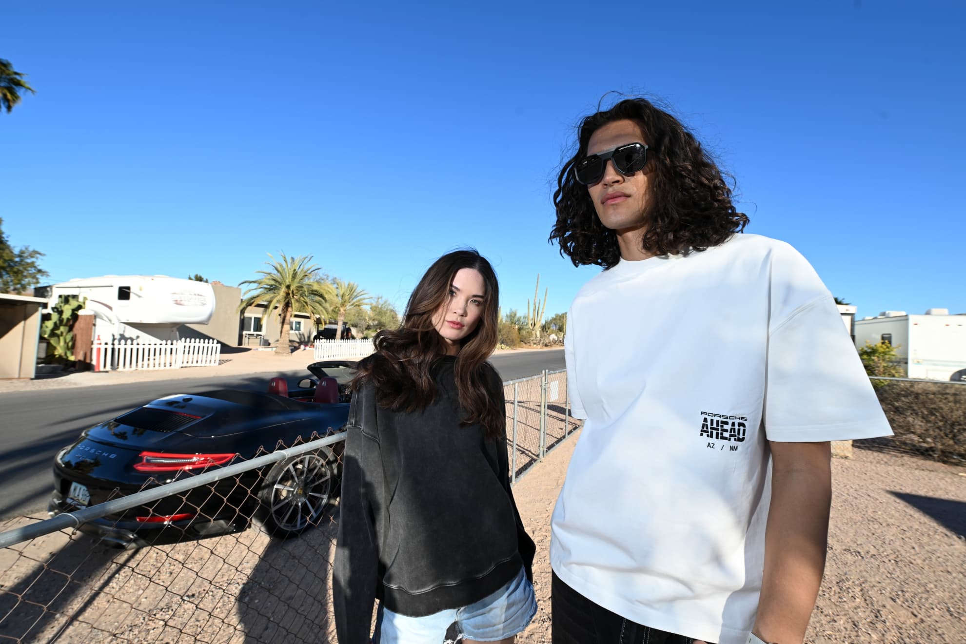 Man and woman weearing Porsche AHAED Fashion in front of Porsche