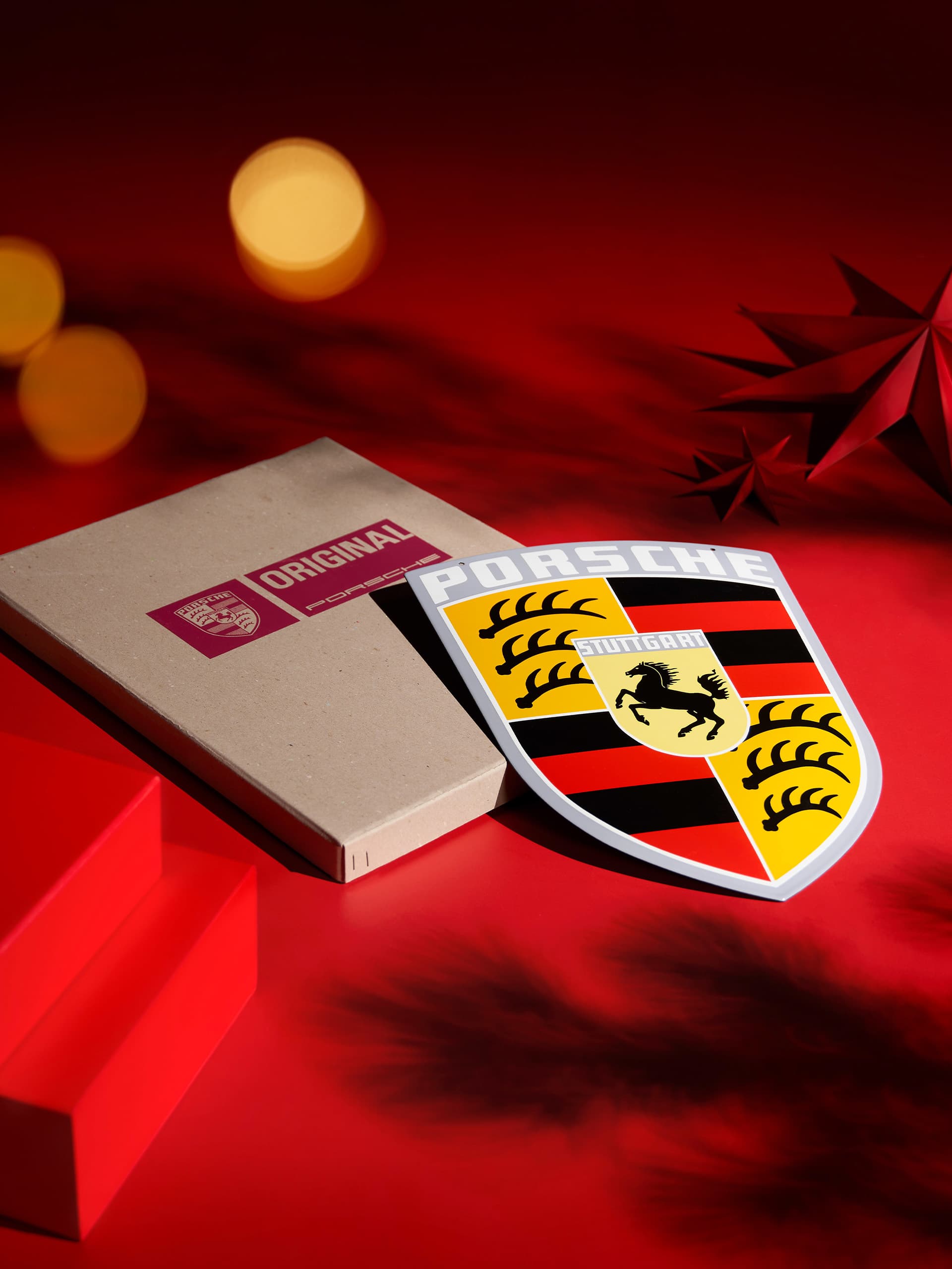 Porsche emblem and branded box on red and gold background with stylized tree design.