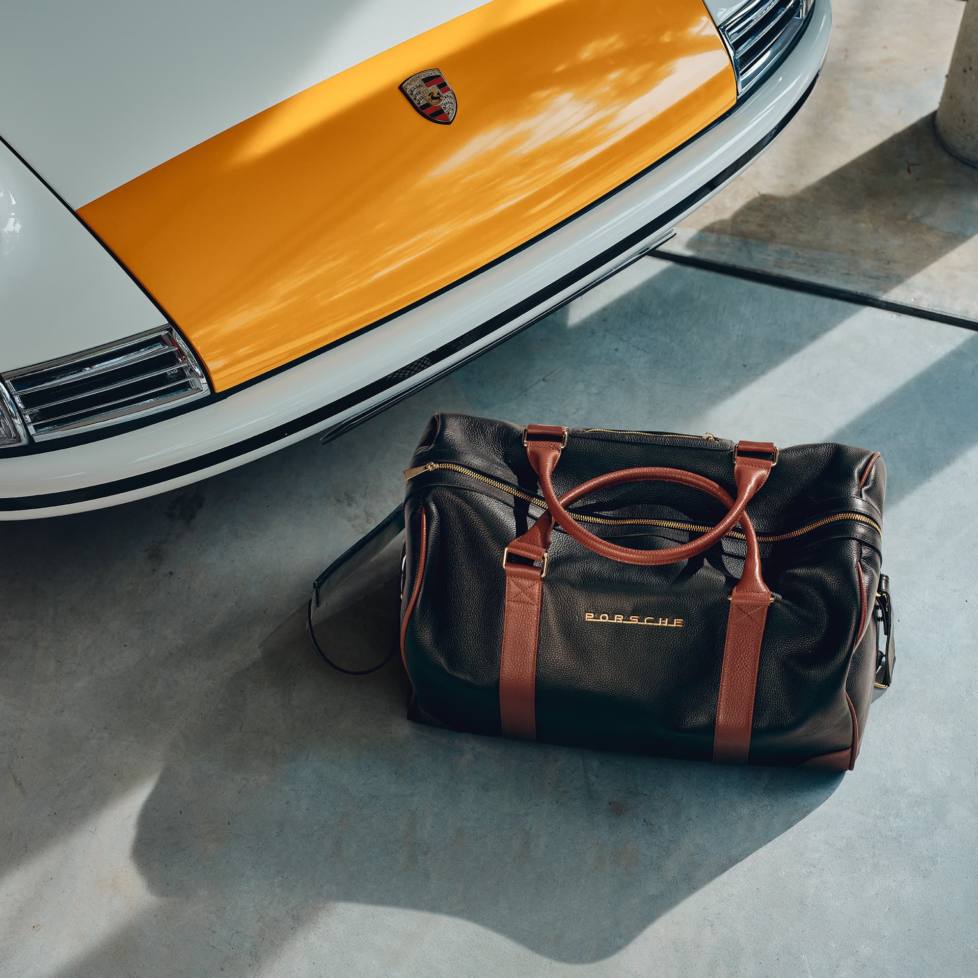 Porsche Classic Touring Bag on the ground next to a historic Porsche 911