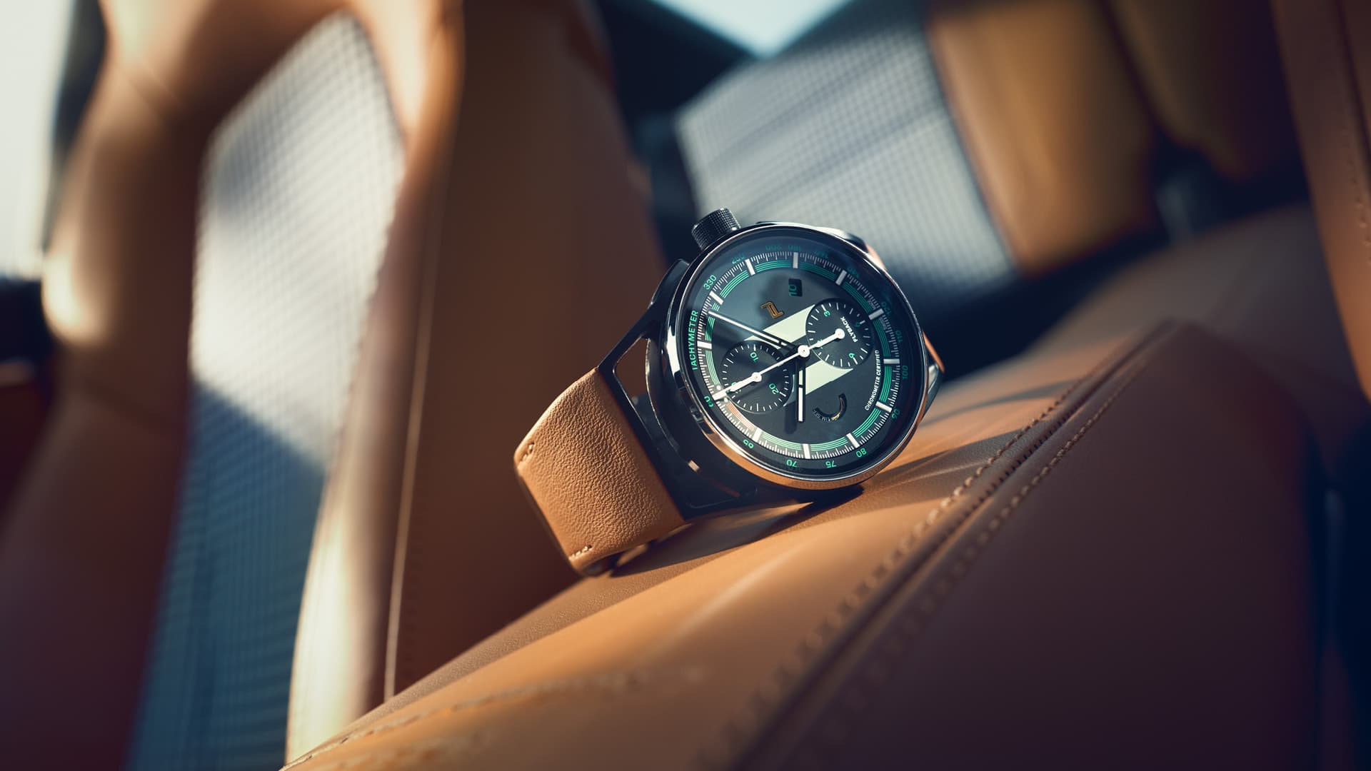The Chronograph 911 Sport Classic with brown leather strap on a brown leather seat