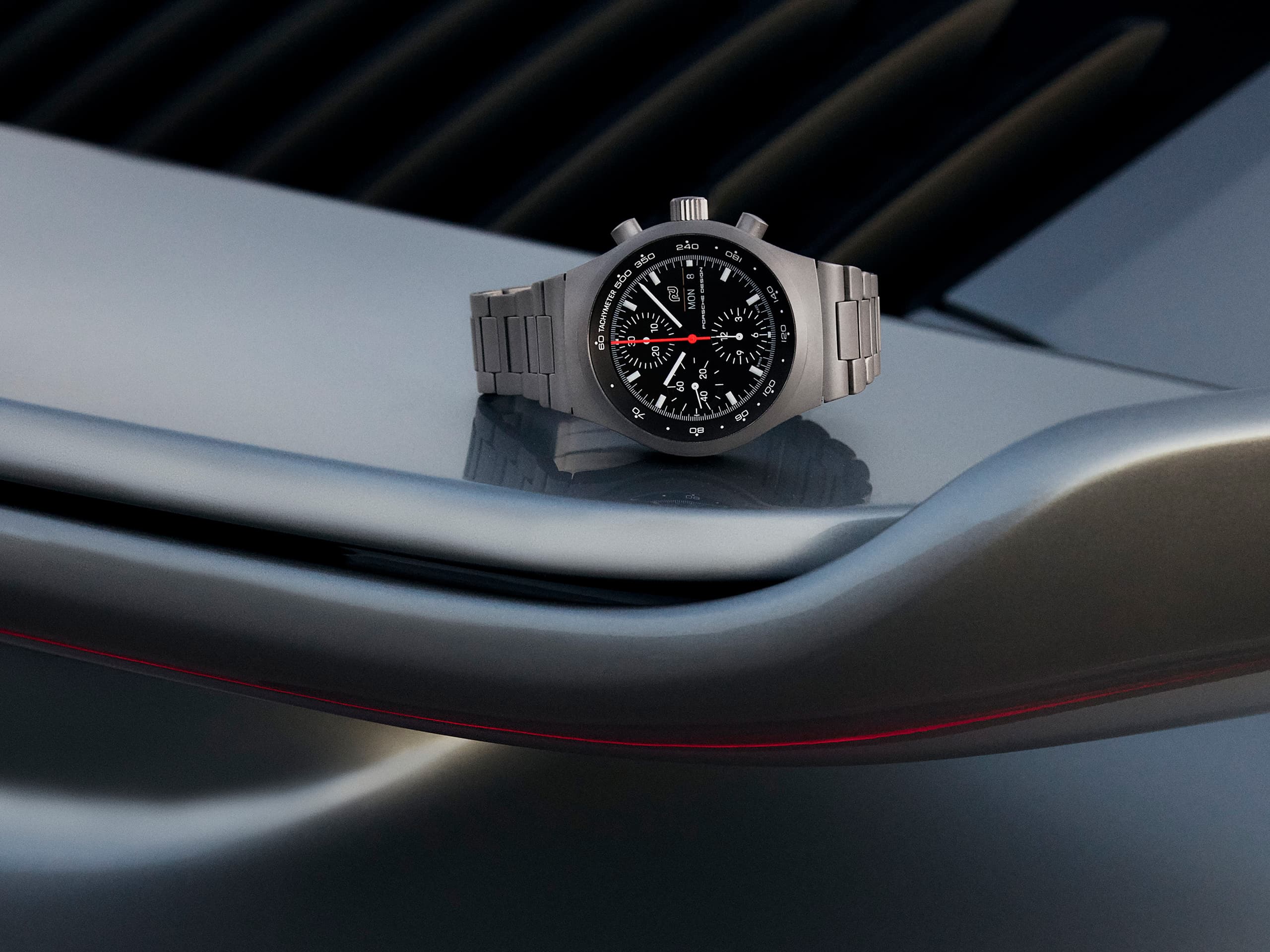 Chronograph 1 - 1975 Limited Edition lies on the rear spoiler of a Porsche 911 in blue