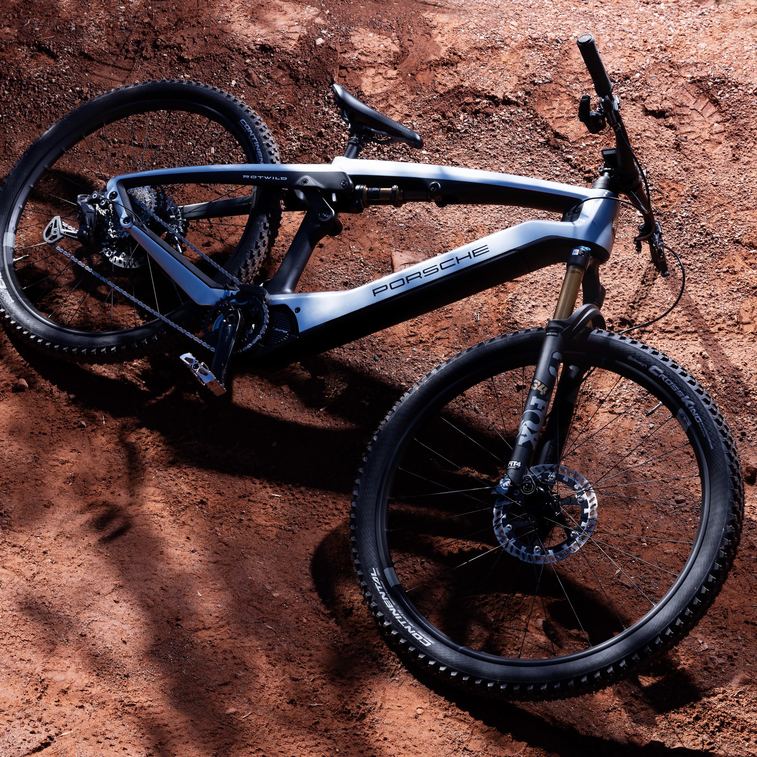 Sleek black and silver Porsche mountain bike on a sunlit, reddish-brown dirt path