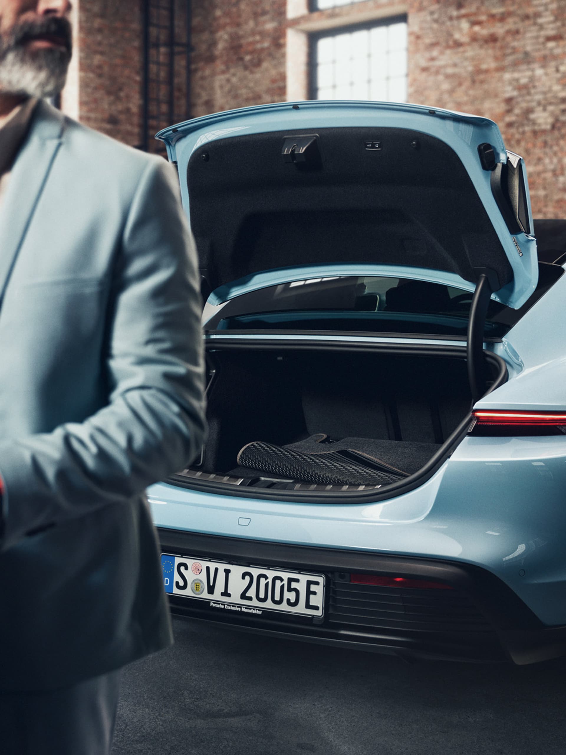 You can see a man standing in front of a Porsche Taycan with an open roofbox