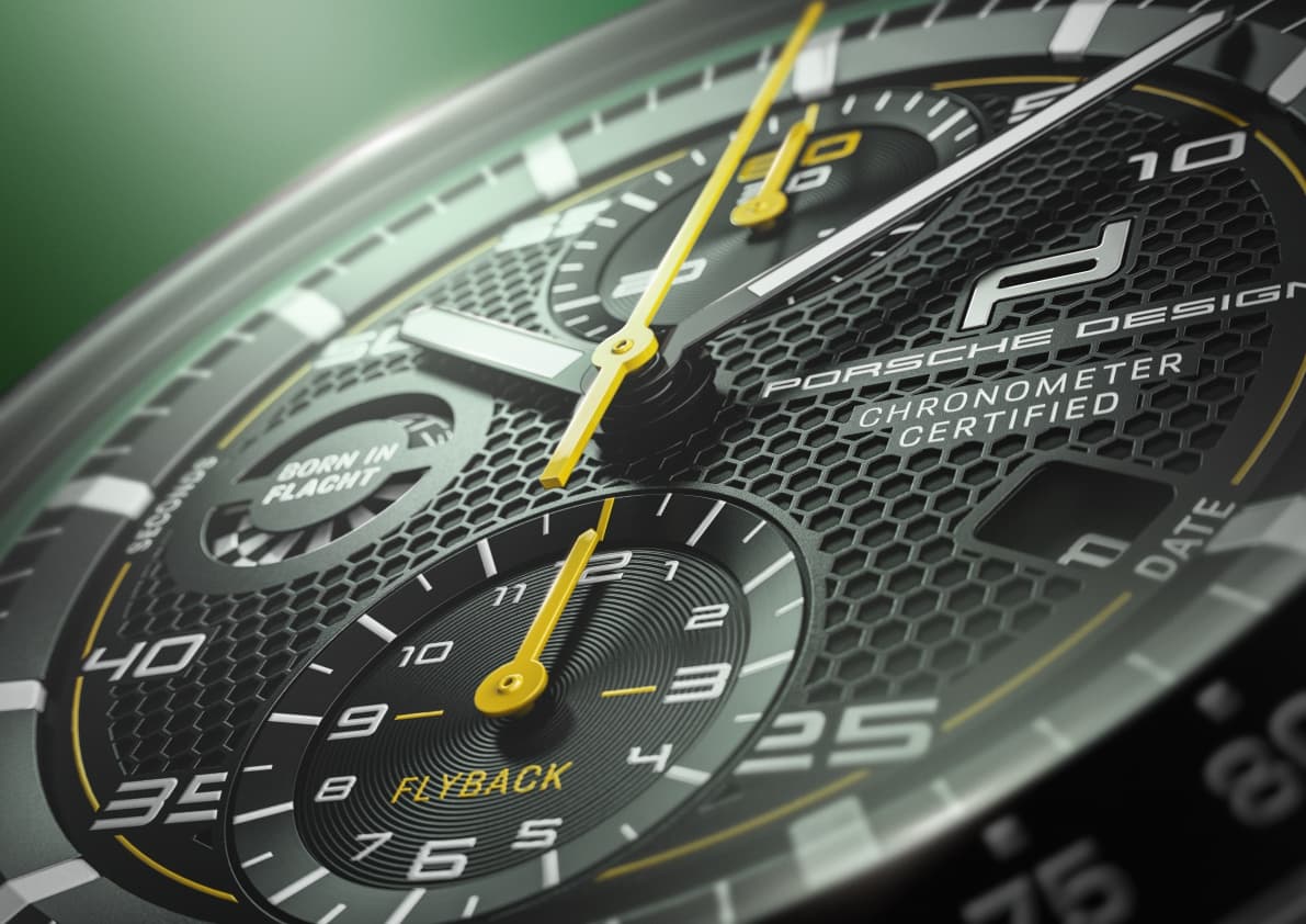 Zbliżenie tarczy czarnego chronografu Porsche Design z fakturą plastra miodu i żółtymi wskazówkami.