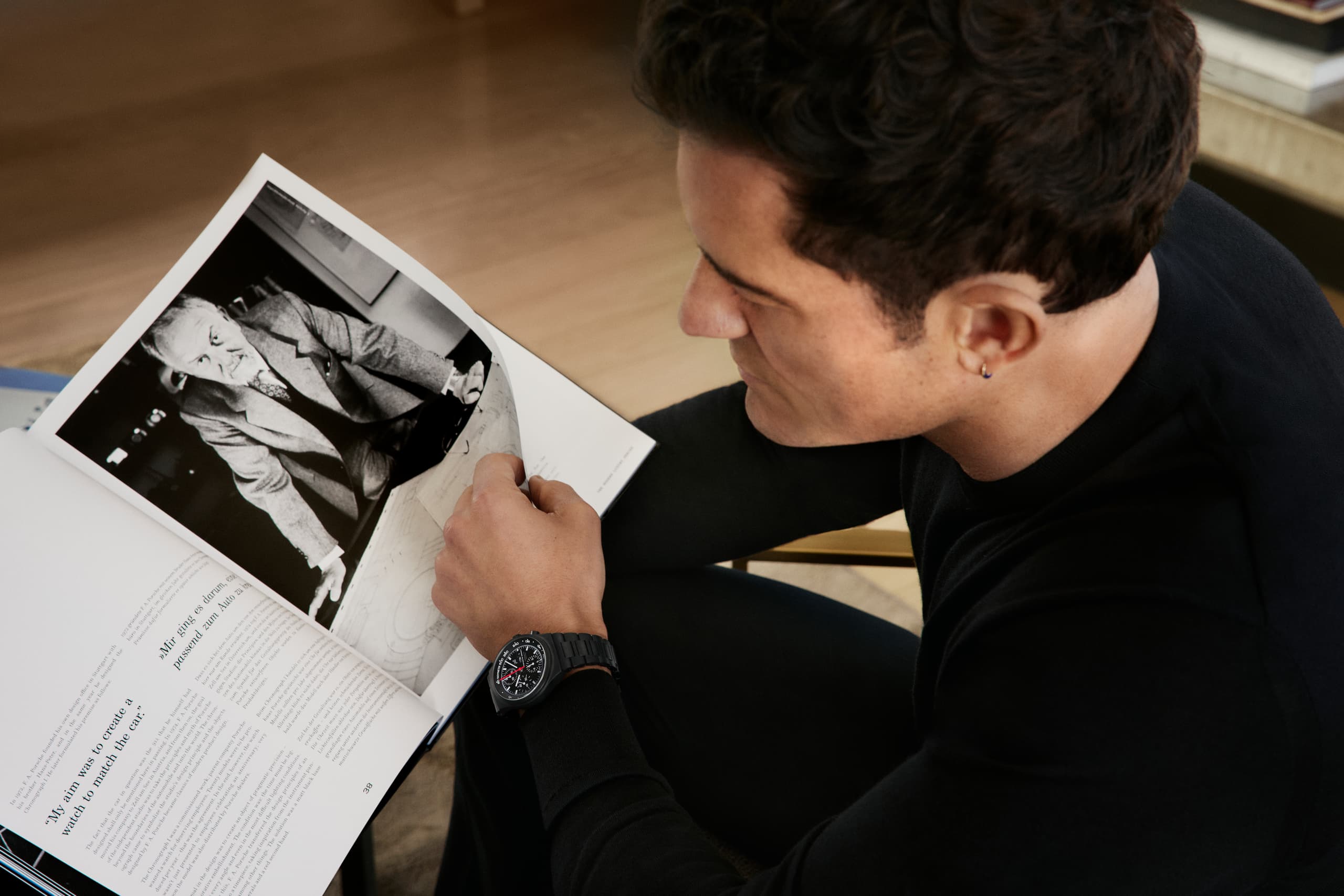 Orlando Bloom wearing the Chronograph 1 - All Black Numbered Edition and reading a magazin article about Prof. Ferdinand Alexander Porsche.