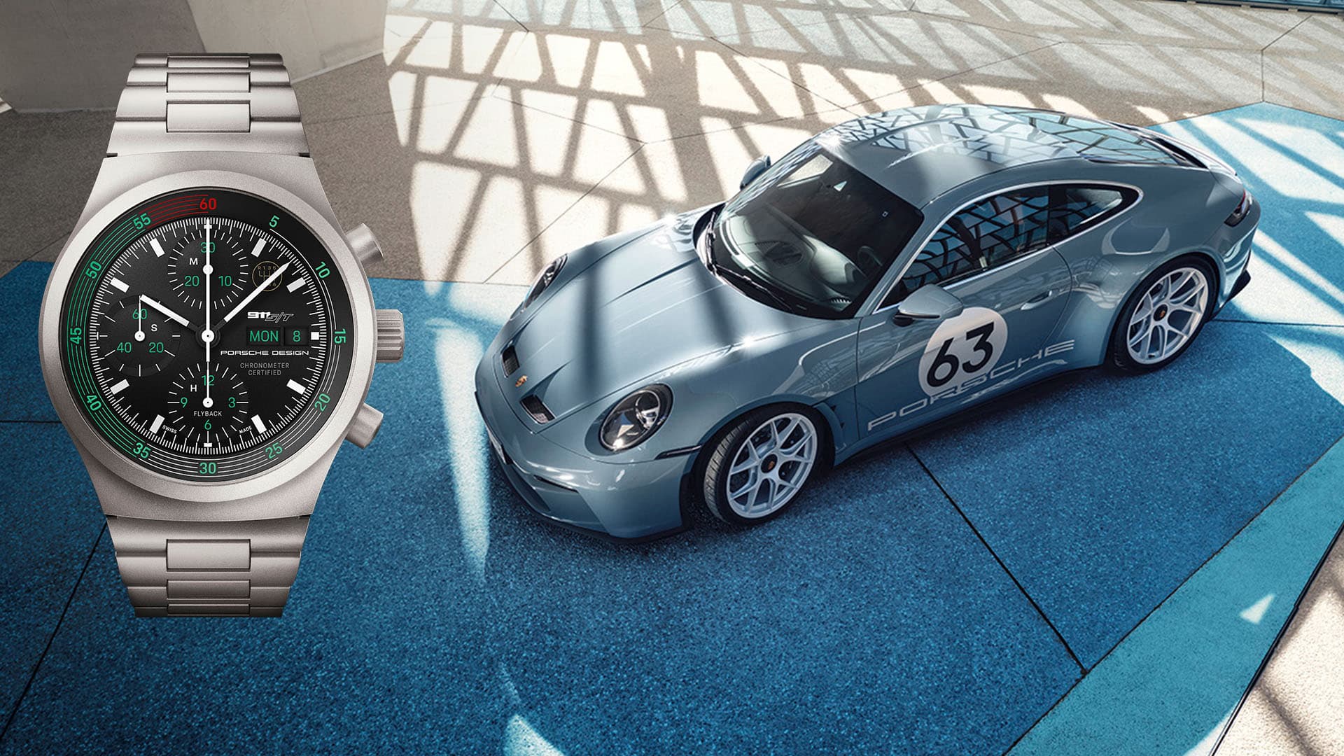 Srebrny zegarek chronograf Porsche Design obok niebieskiego Porsche 911 z numerem 63, na niebieskim tle