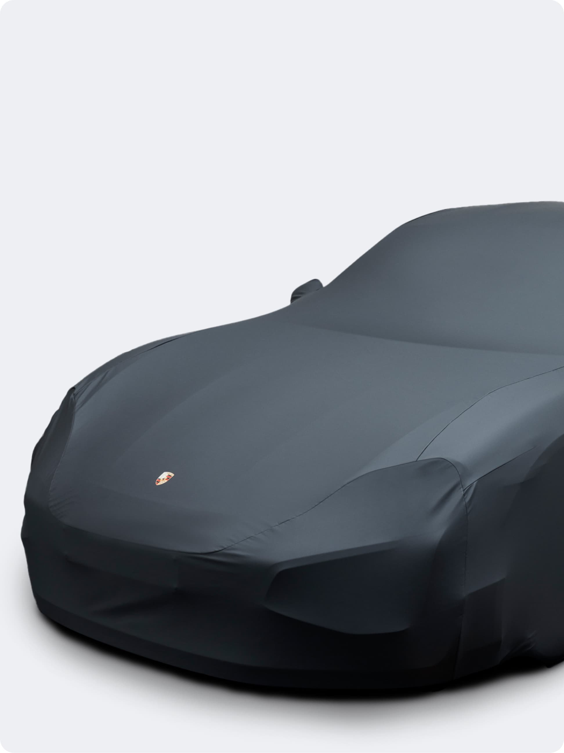 You can see a car beneath a black car cover from Porsche on a white background