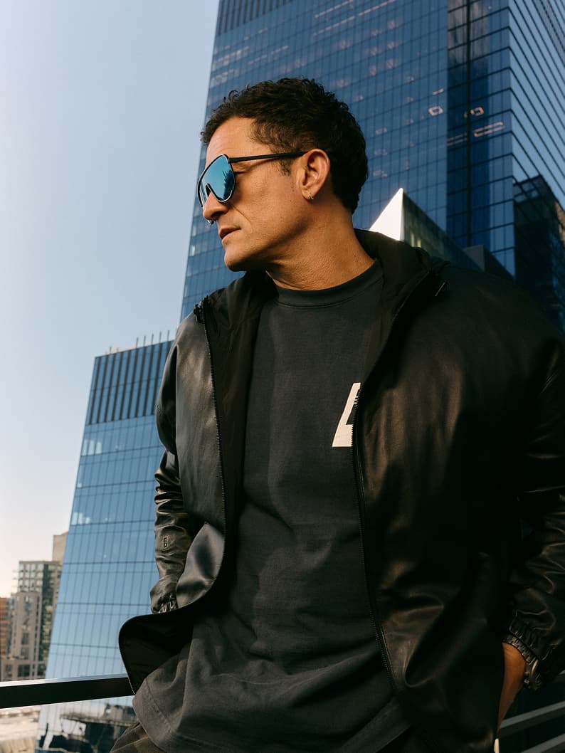 Mann mit Porsche Design Sonnenbrille und dunkler Kleidung vor einer Skyline
