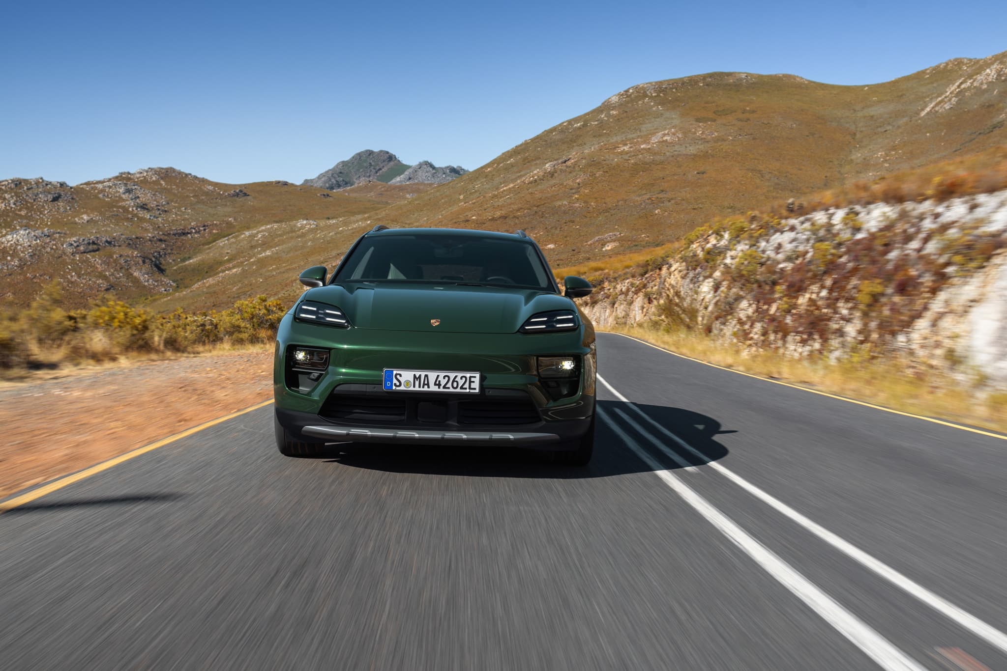 Oakgreen Porsche Macan fom the front driving on a road