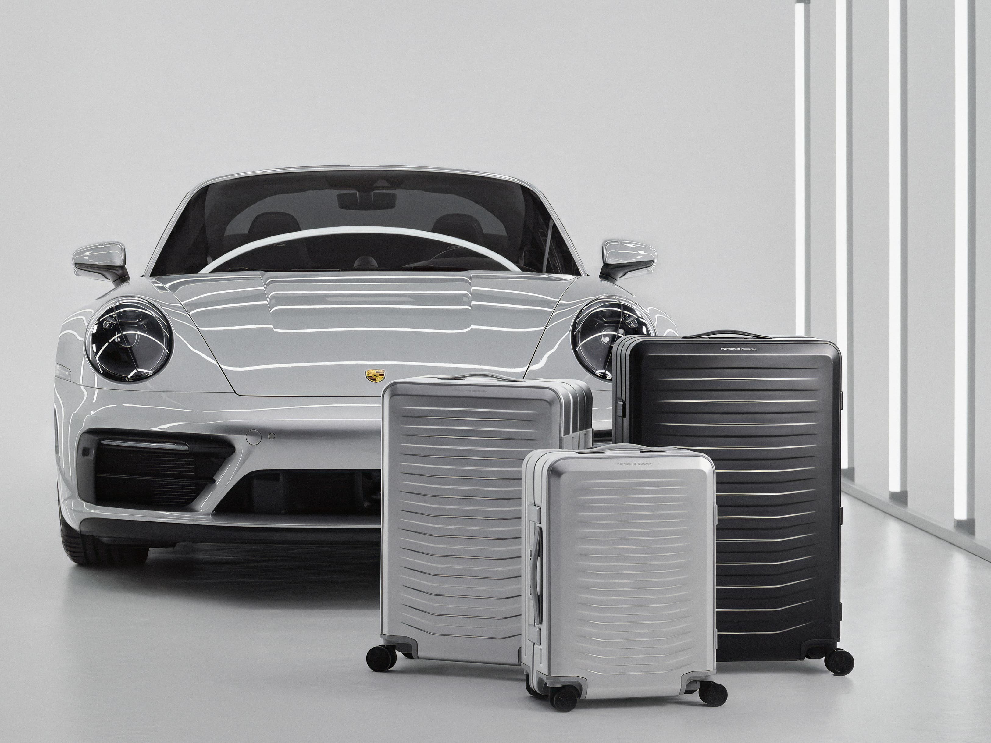 Linia produktów Porsche Design Roadster Aluminum na tle samochodu Porsche
