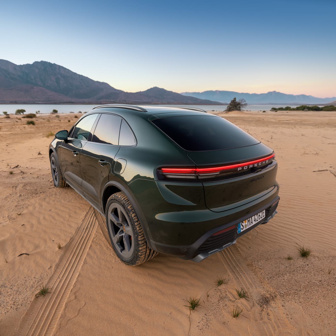 View of the rear of a darkgreen Porsche Macan in a dusty landscape