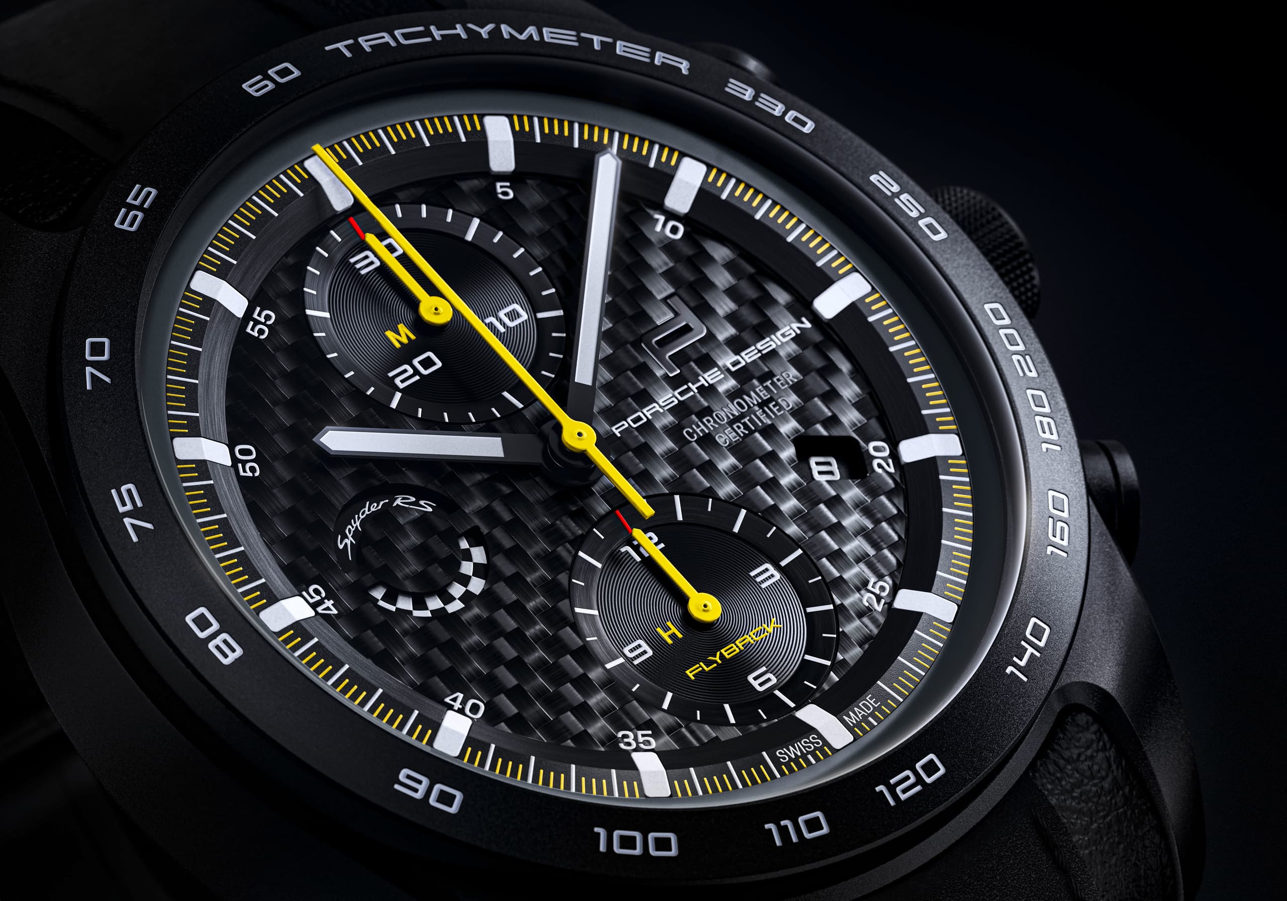 Zbliżenie na chronograf Porsche Design z karbonową tarczą, żółtymi wskazówkami i czarnym pierścieniem tachymetru na bezelu