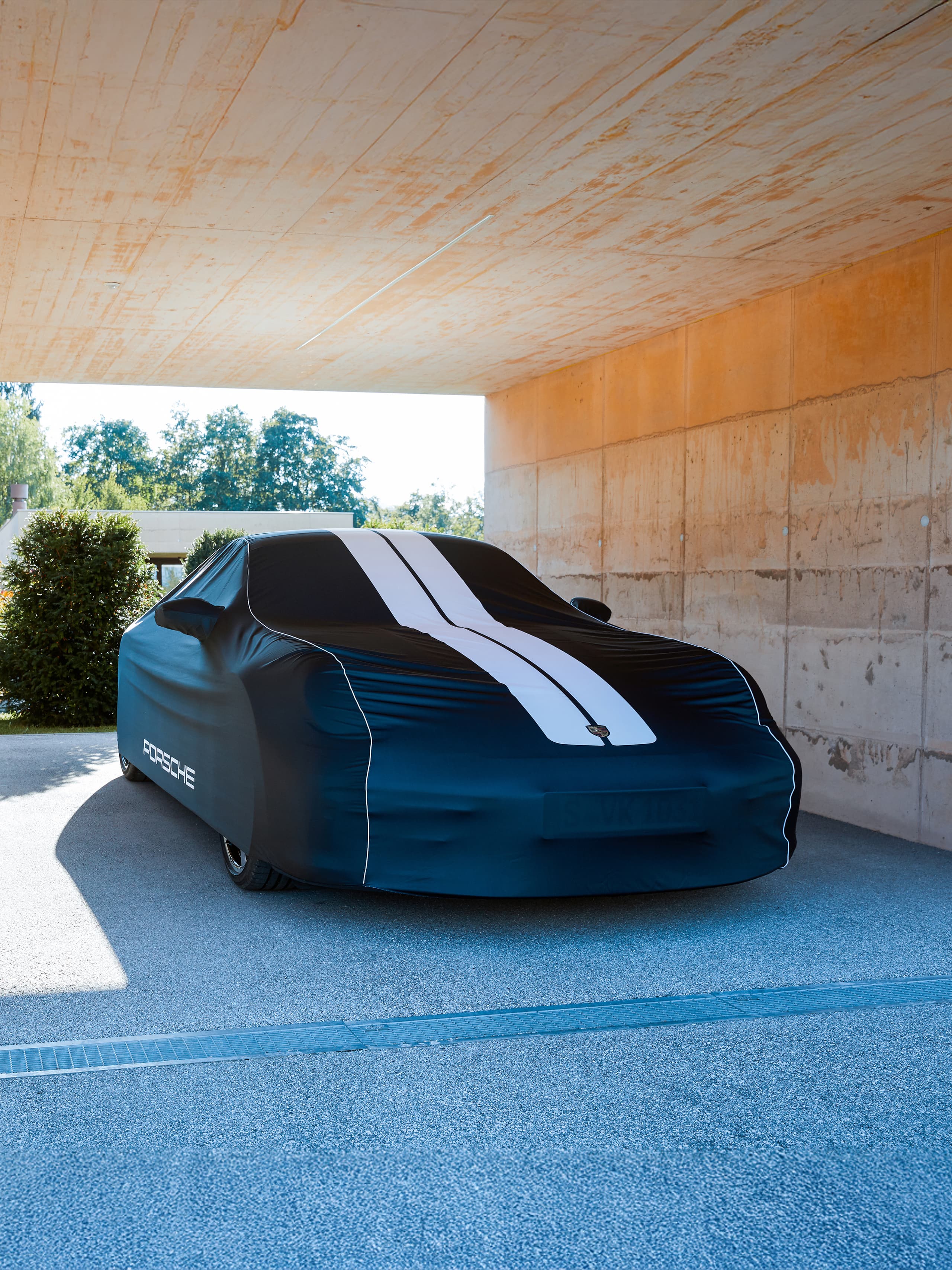 You can see a car beneath a black car cover in the outside