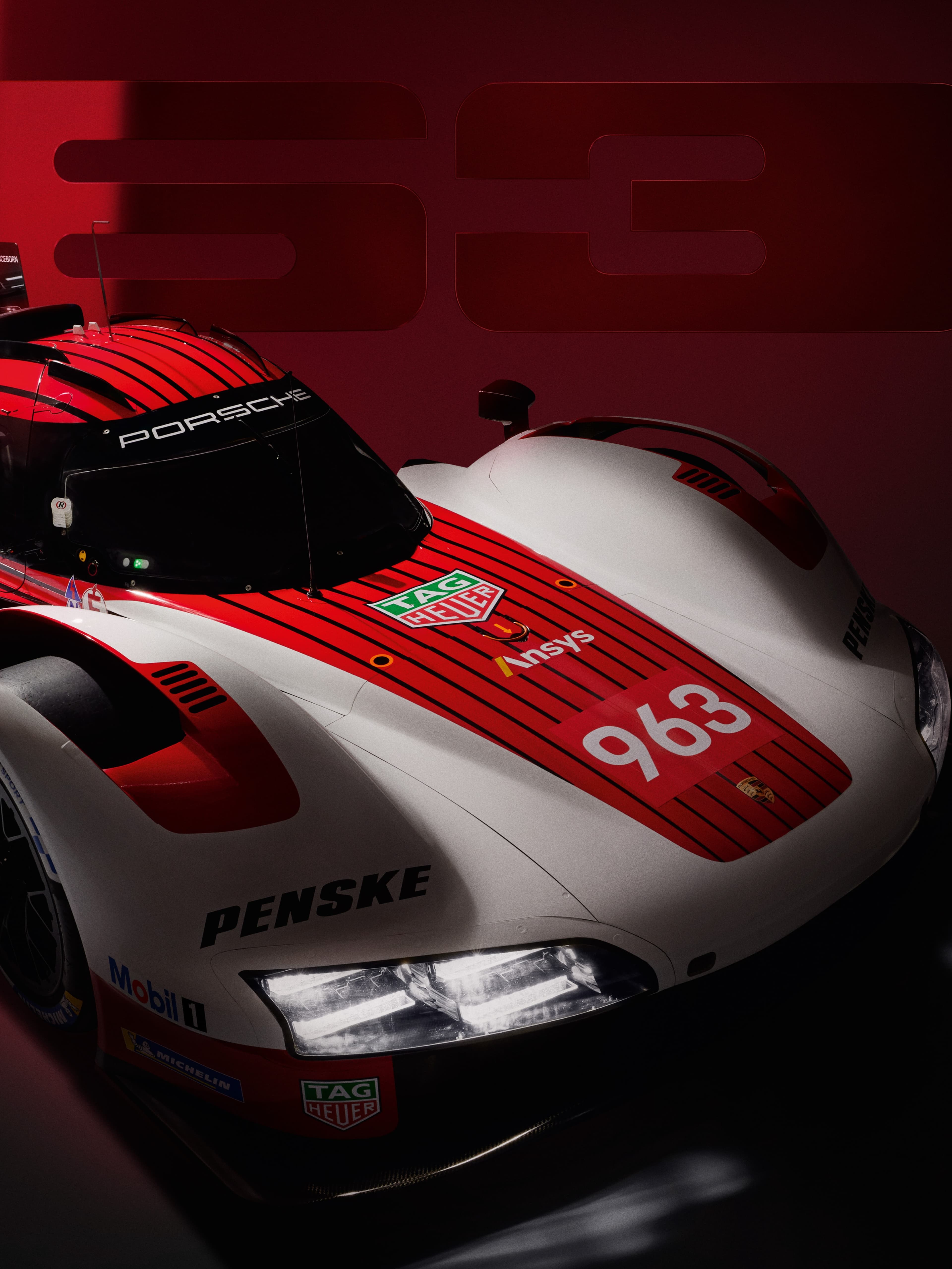 White Porsche race car with gold wheels, red and blue accents, next to a matching barrel with number 26 on a dark background.