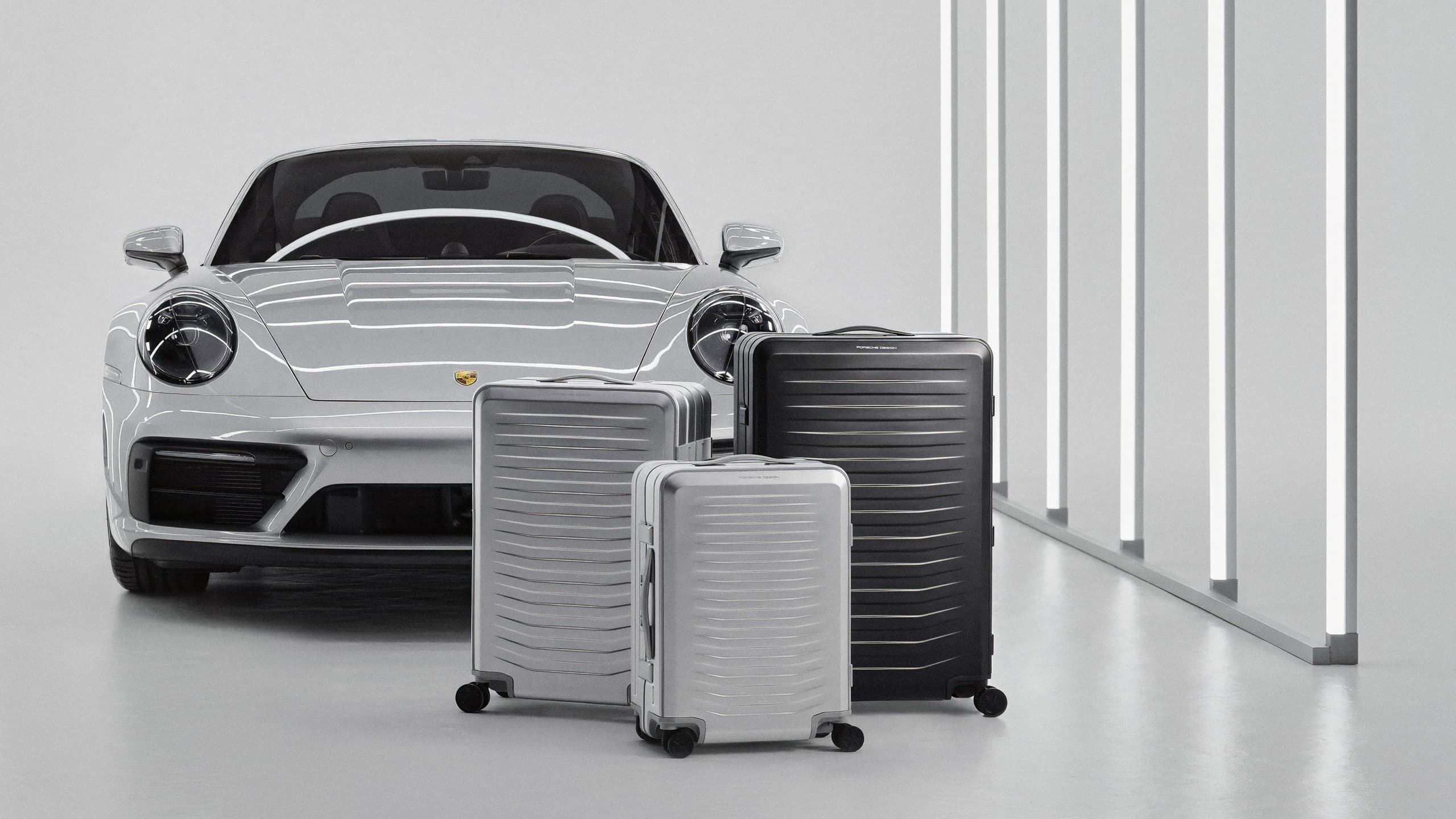 Porsche Design Roadster Aluminum Trolley Collection in front of Porsche car.