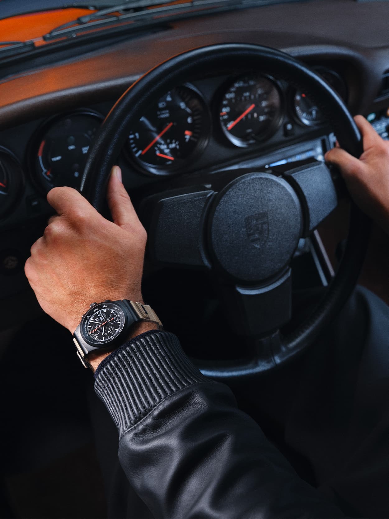 Close up of a man-s hands holding a steering wheel wearing a Porsche Design 50Y Chrono watch on his left wrist
