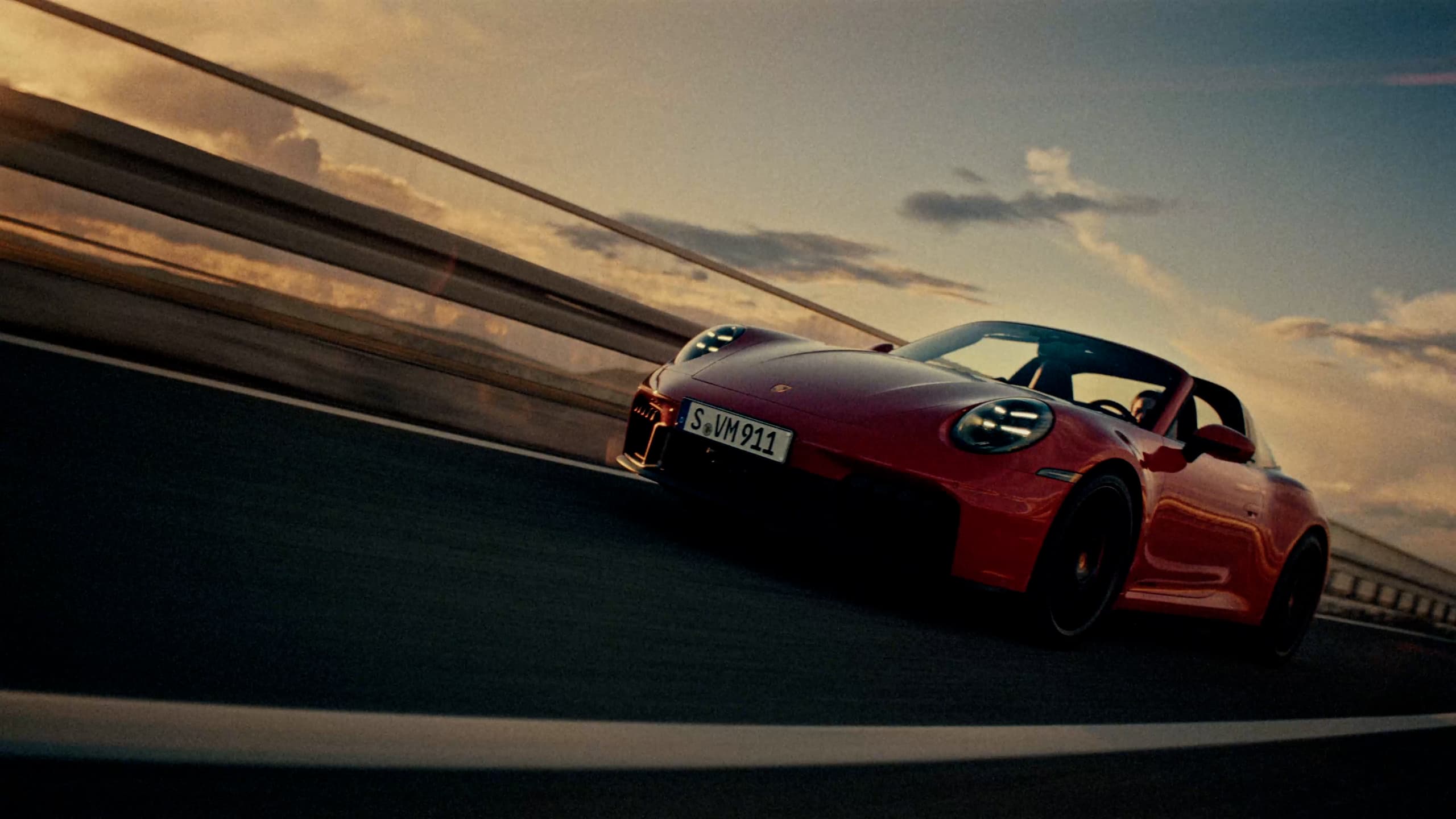 Red Porsche car is driving on a road